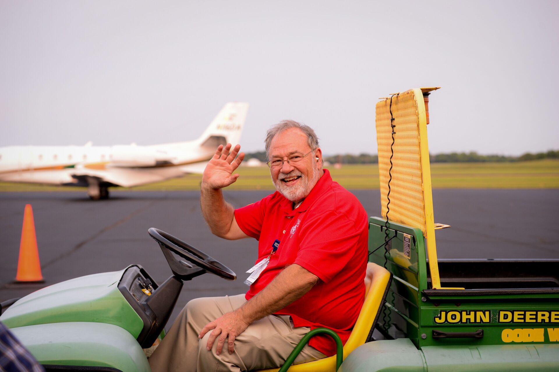 A man in a red shirt is sitting in a john deere tractor