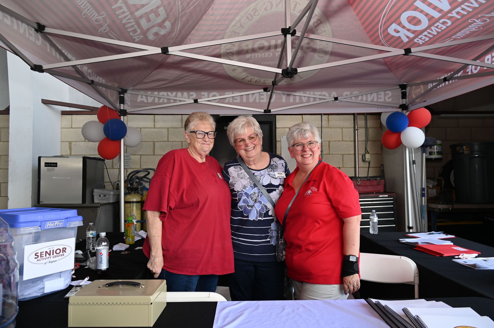 Three women are posing for a picture in front of a tent.