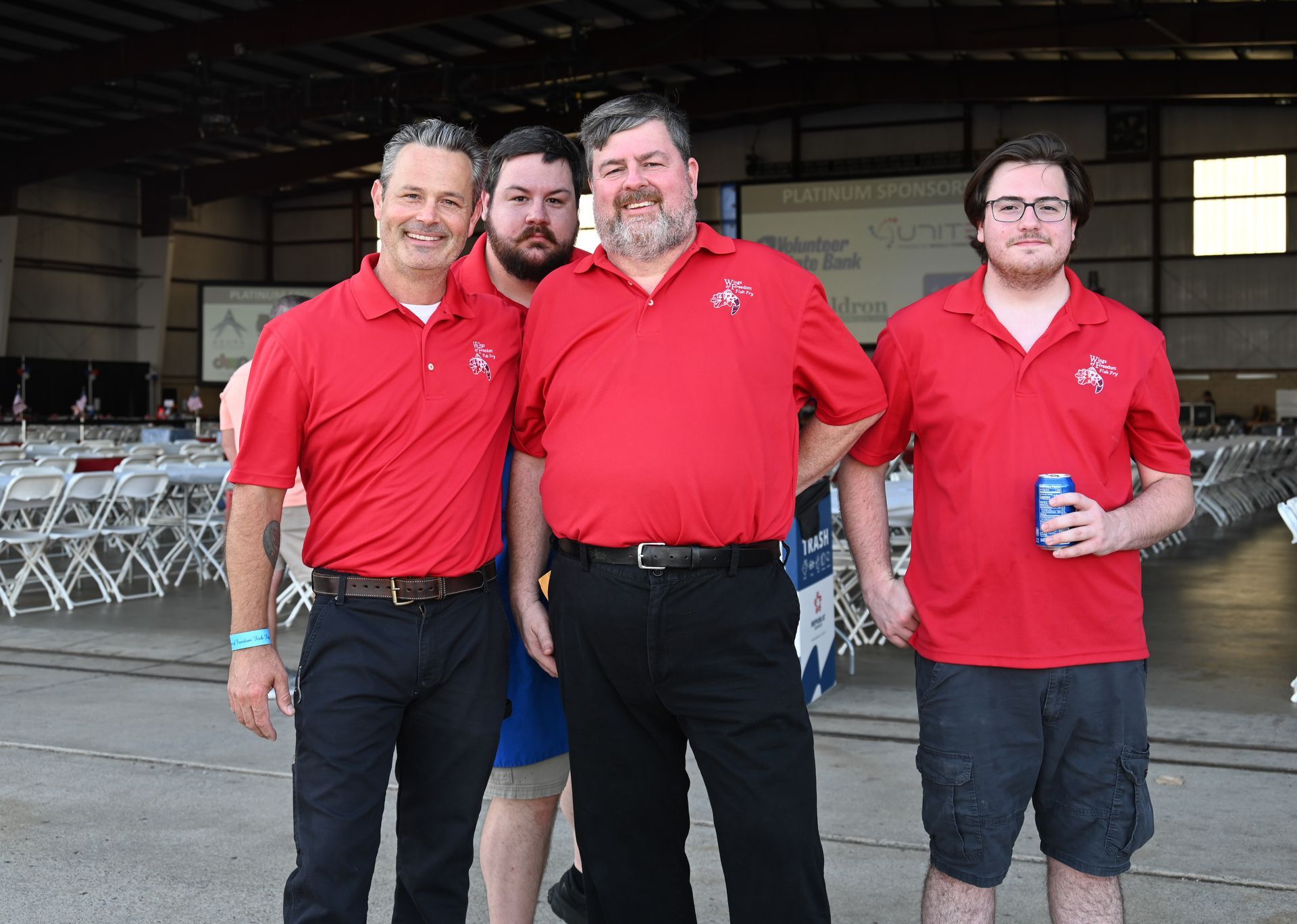 A group of men in red shirts are posing for a picture
