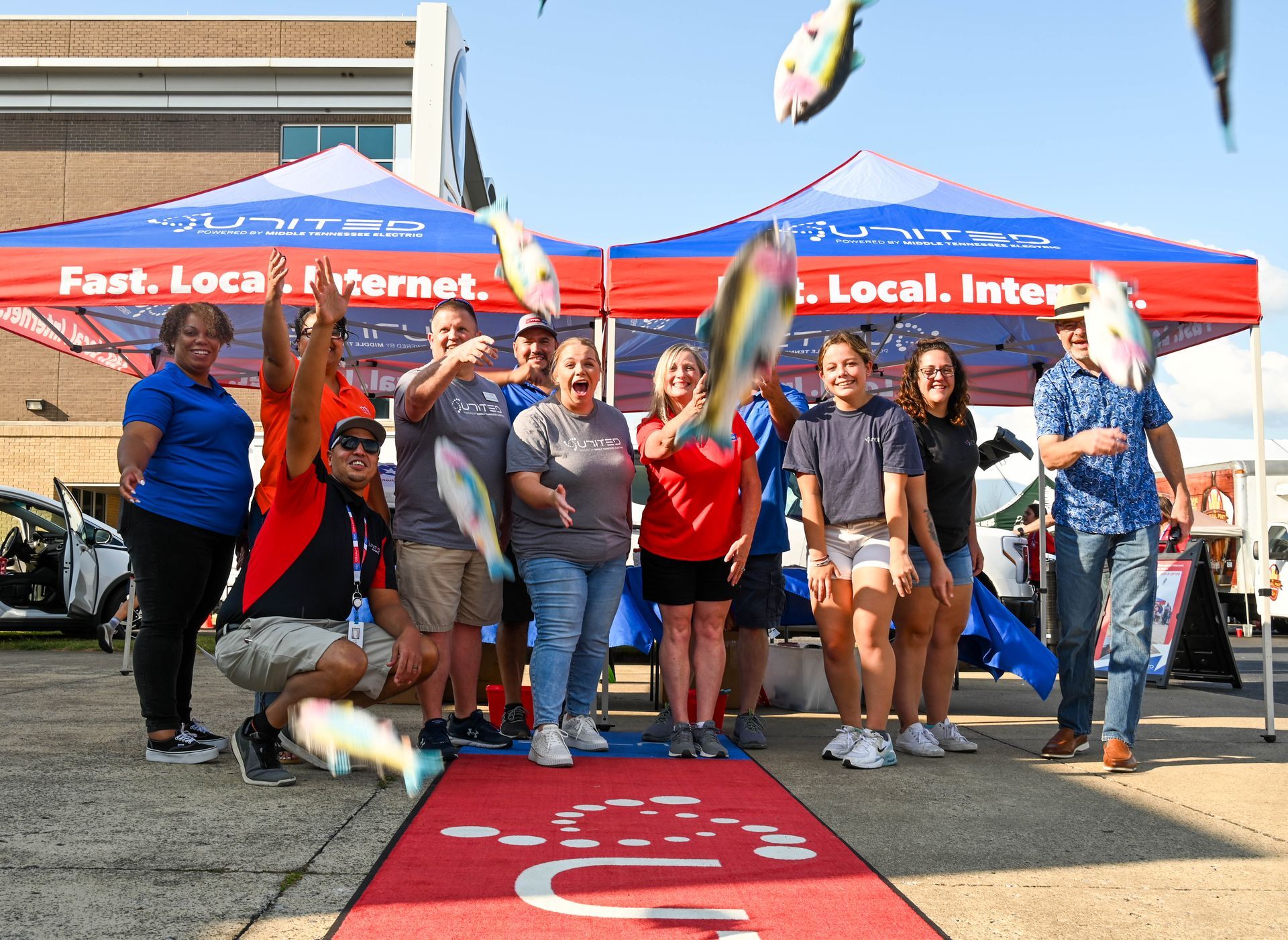 A group of people are standing in front of a tent holding fish.