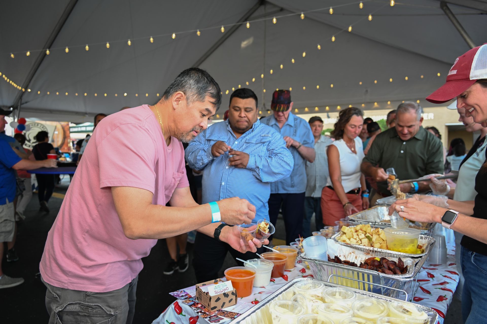 A group of people are standing around a table eating food.