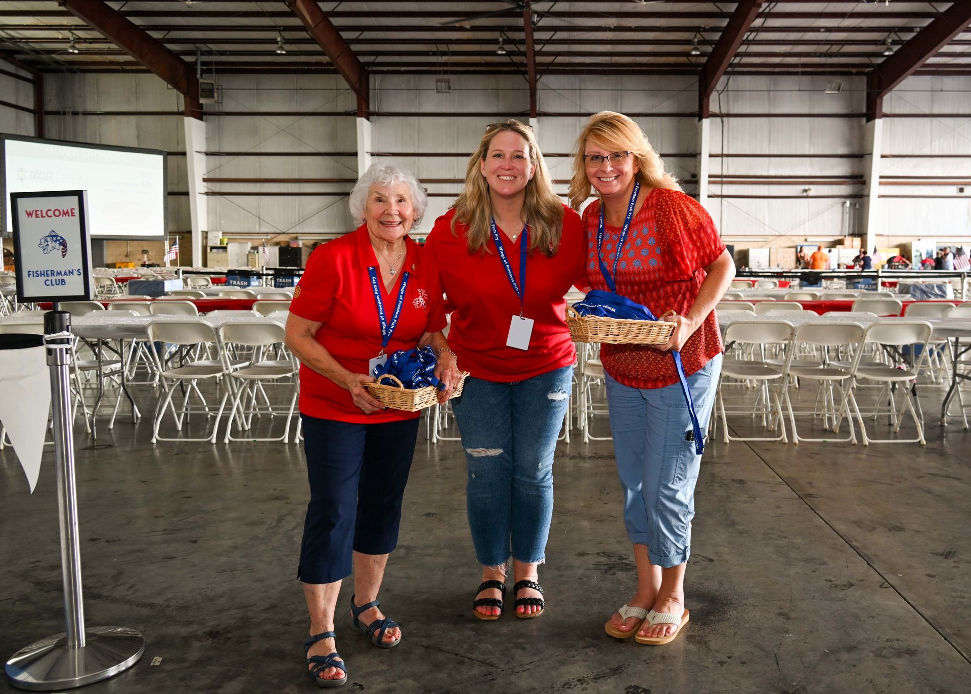 Three women are standing next to each other in a room holding baskets.