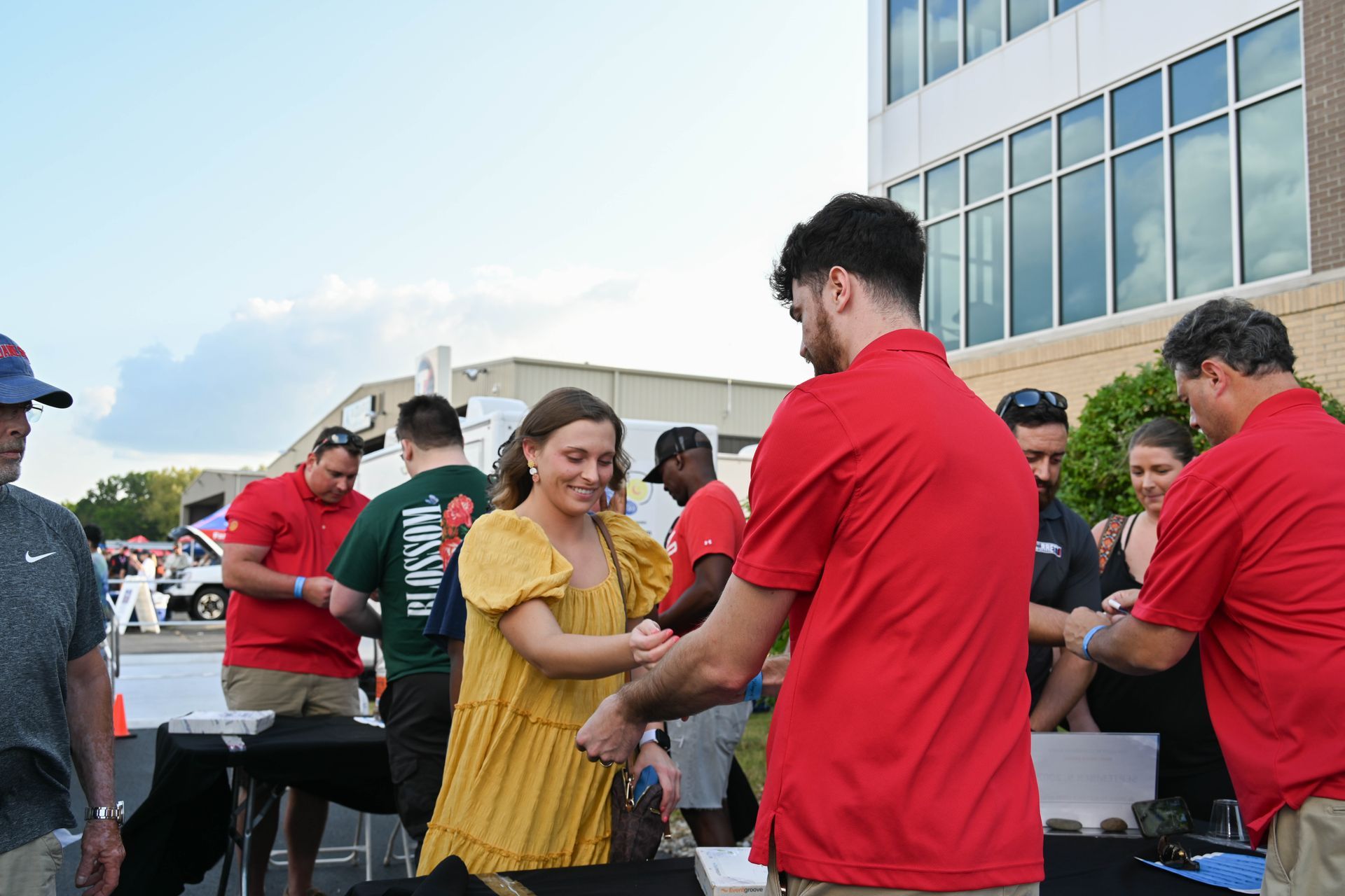 A man in a red shirt is shaking hands with a woman in a yellow dress.