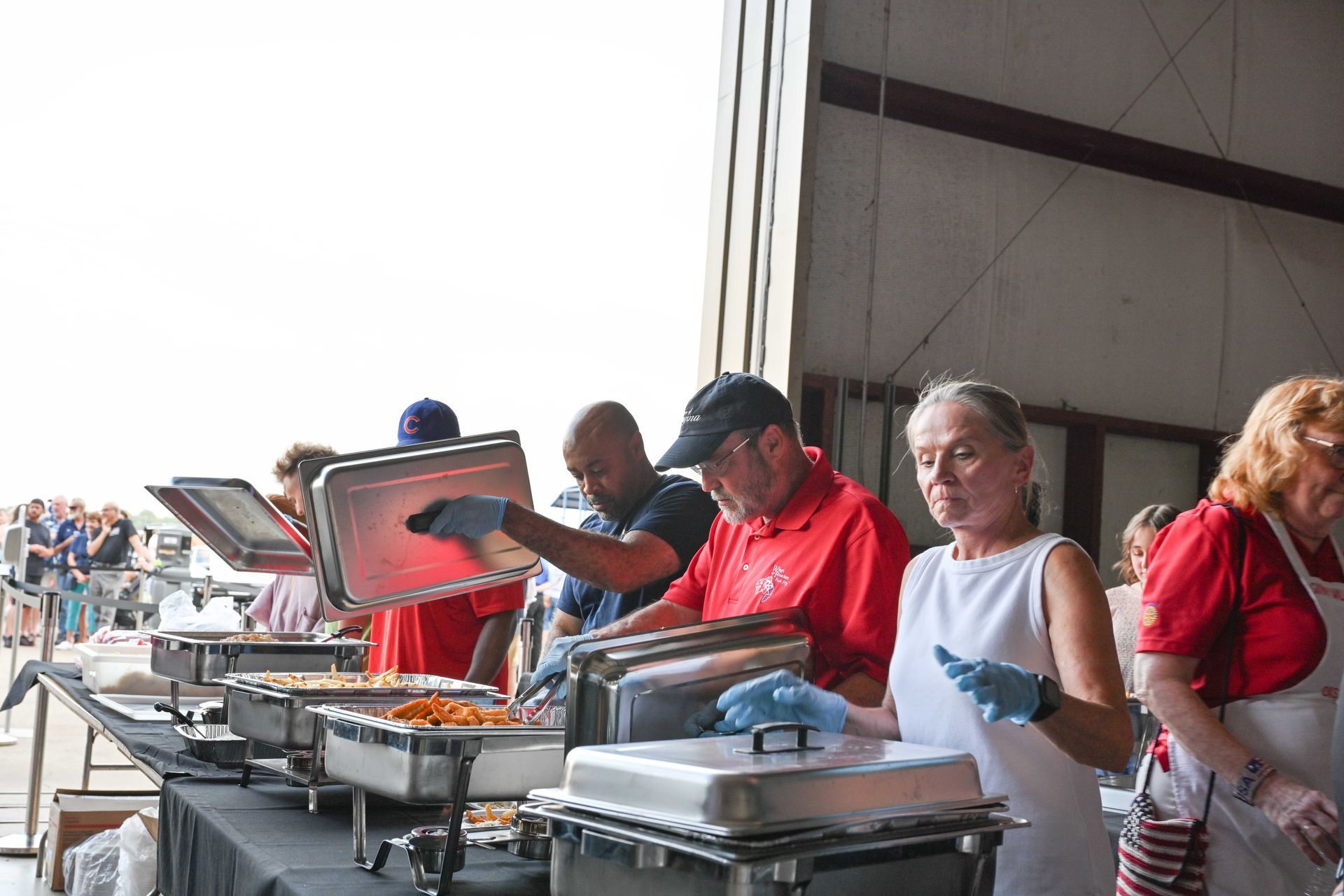 A group of people are standing around a table serving food.