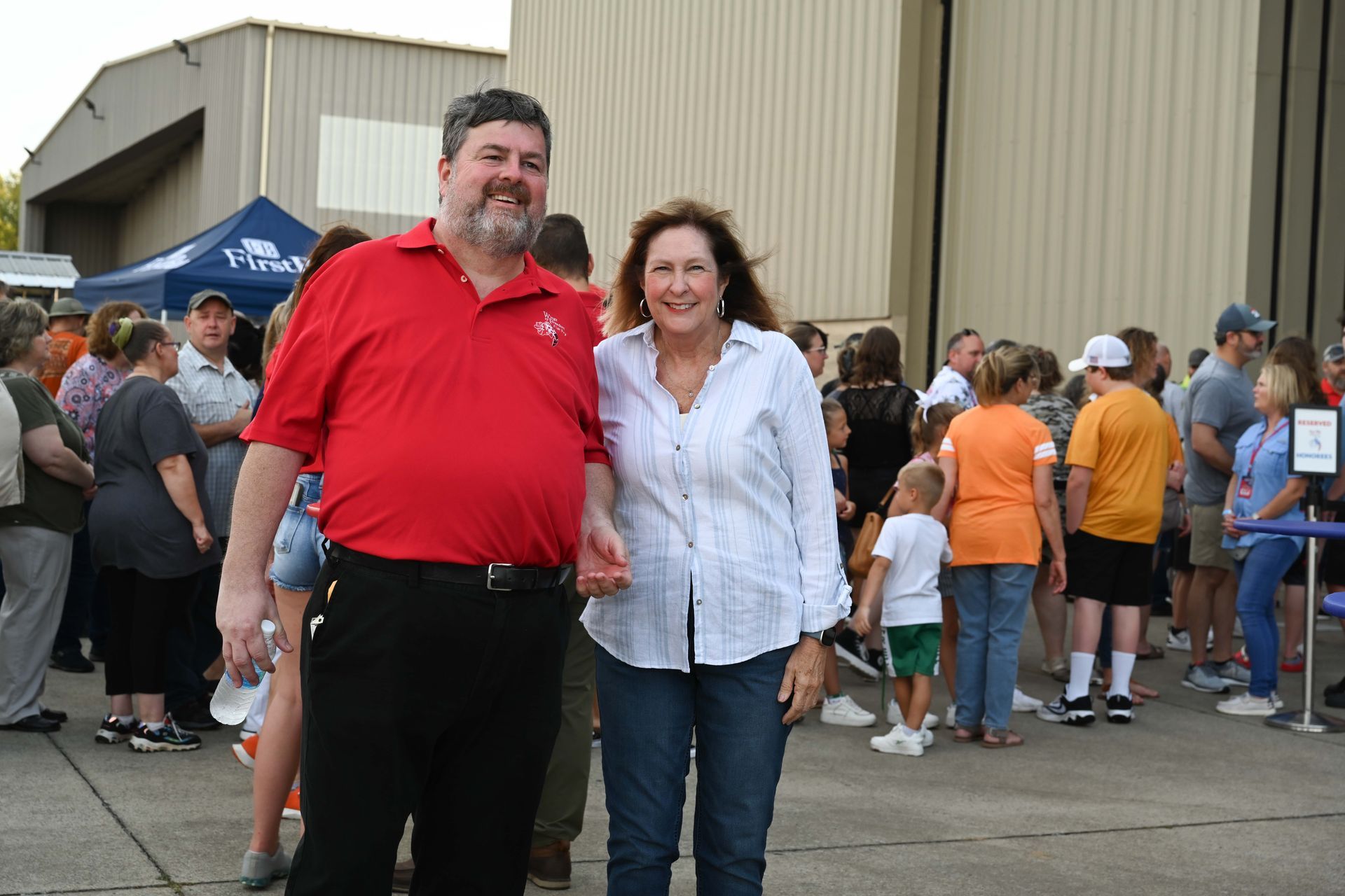 A man and a woman are posing for a picture in front of a crowd of people.