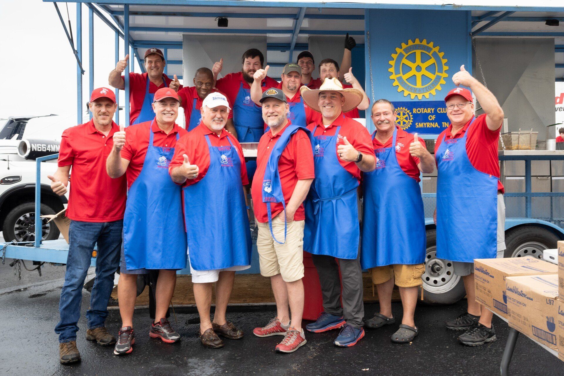 A group of men are posing for a picture in front of a rotary trailer.