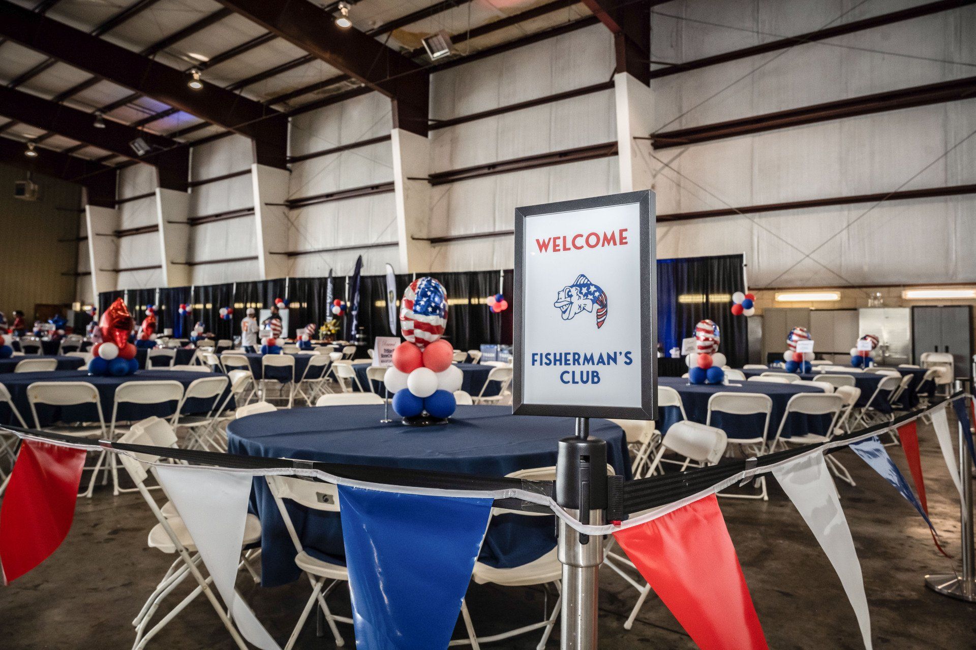 A large room with tables and chairs and a welcome sign.