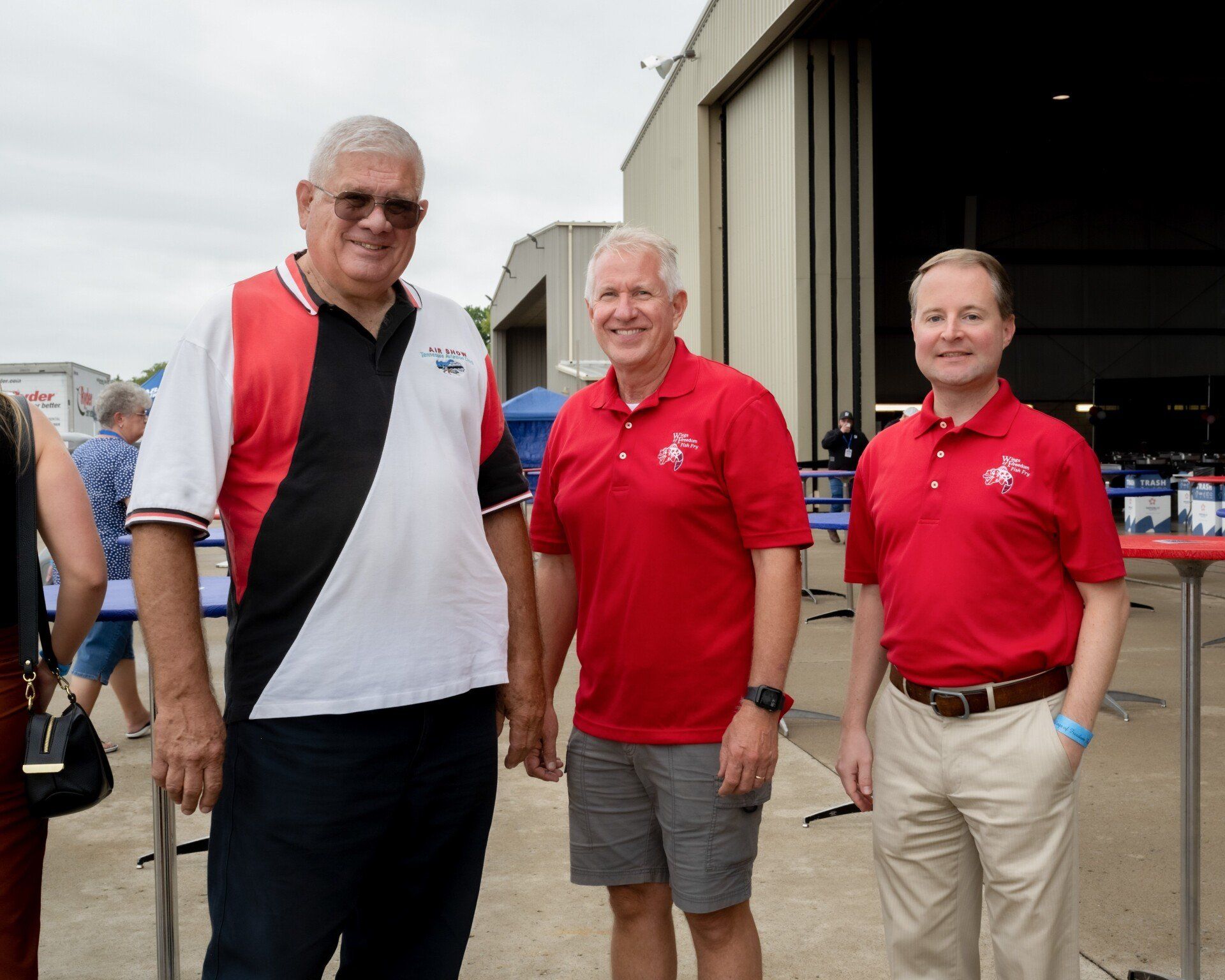 Three men in red shirts are posing for a picture