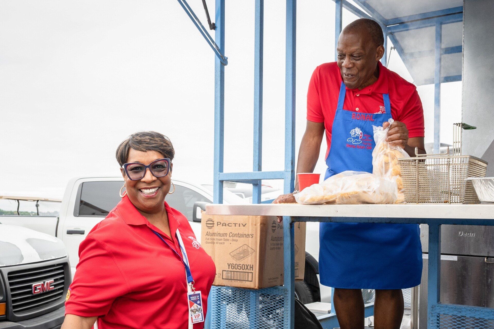 A man and a woman are standing in front of a food truck.