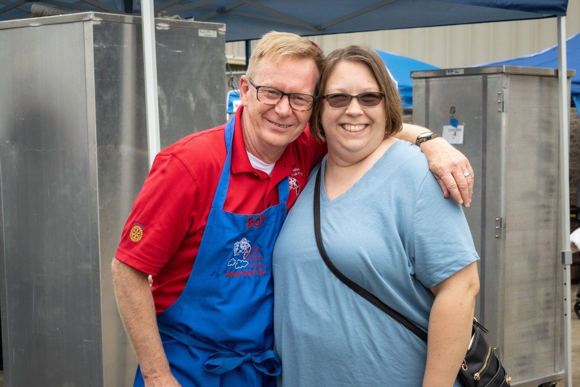 A man and a woman are posing for a picture while wearing aprons.