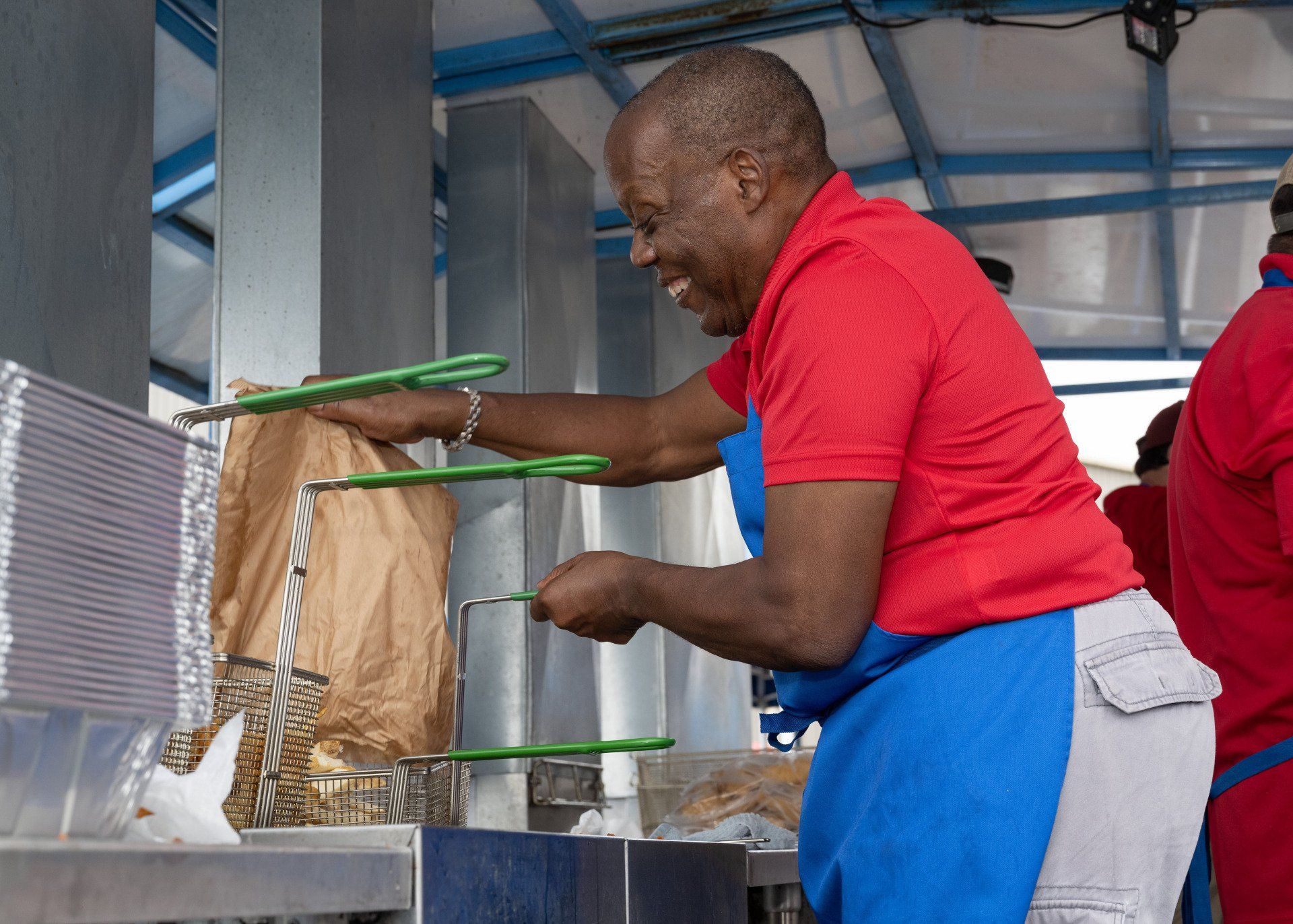 A man in a red shirt and blue apron is preparing food