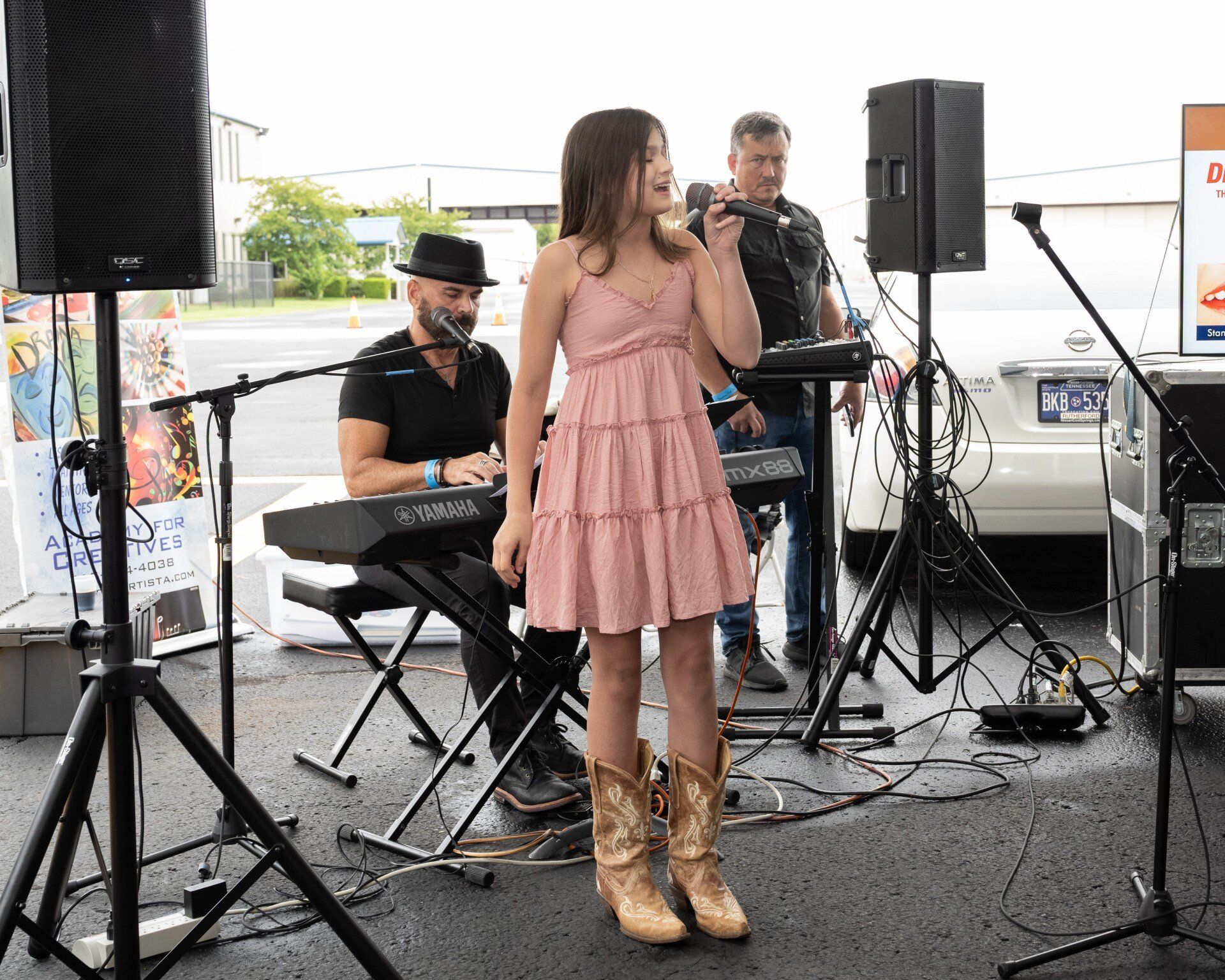 A woman in a pink dress is singing into a microphone while a man plays a keyboard.