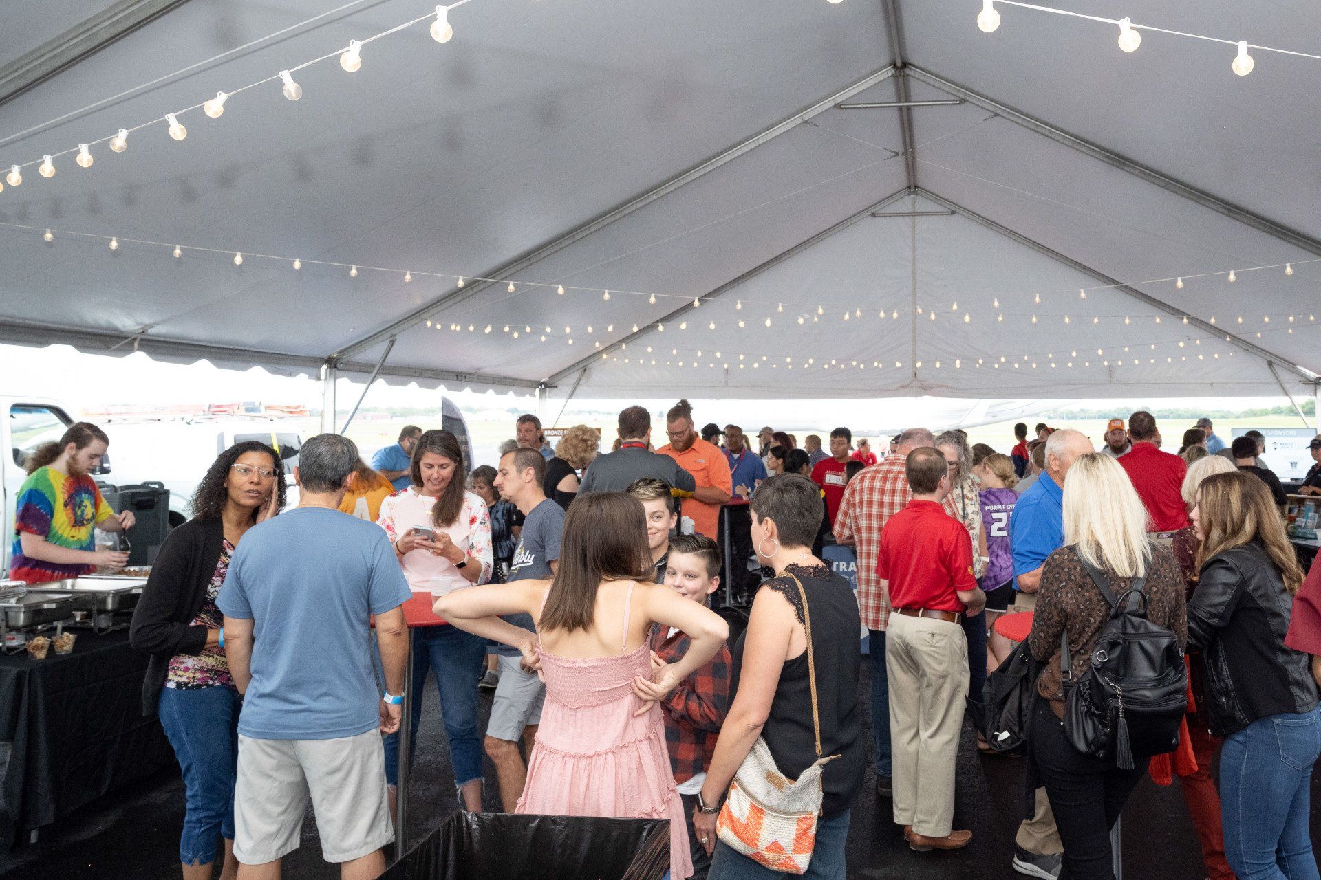 A large group of people are standing under a tent.