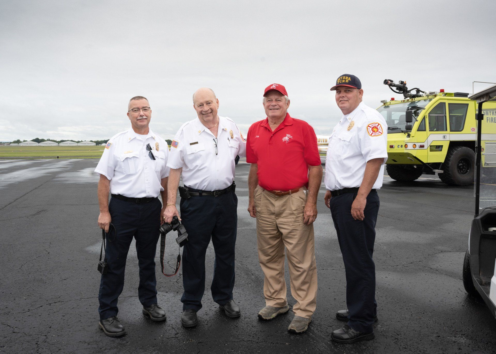 A group of men are standing in front of a fire truck.