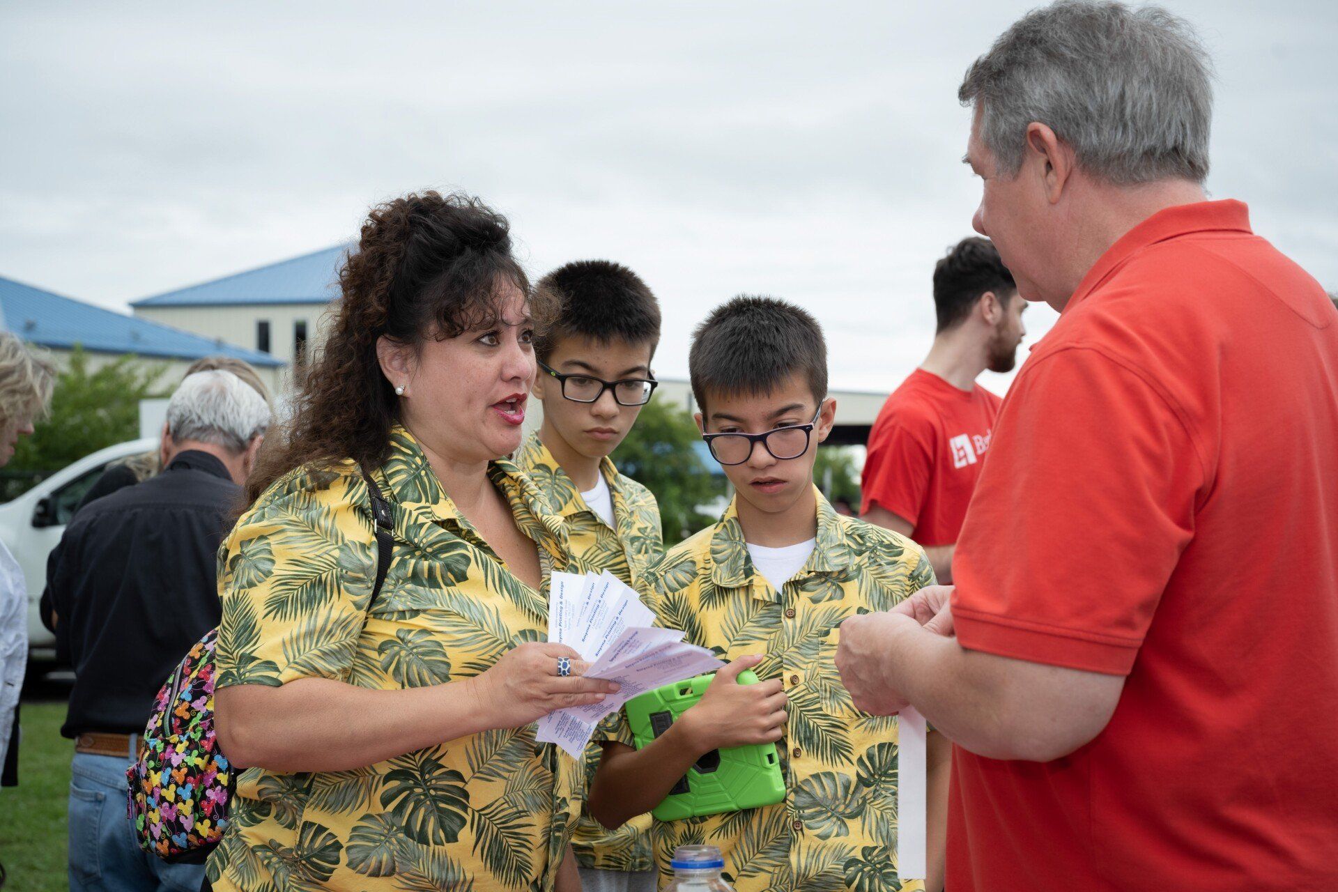 A group of people are standing next to each other talking to a man in a red shirt.
