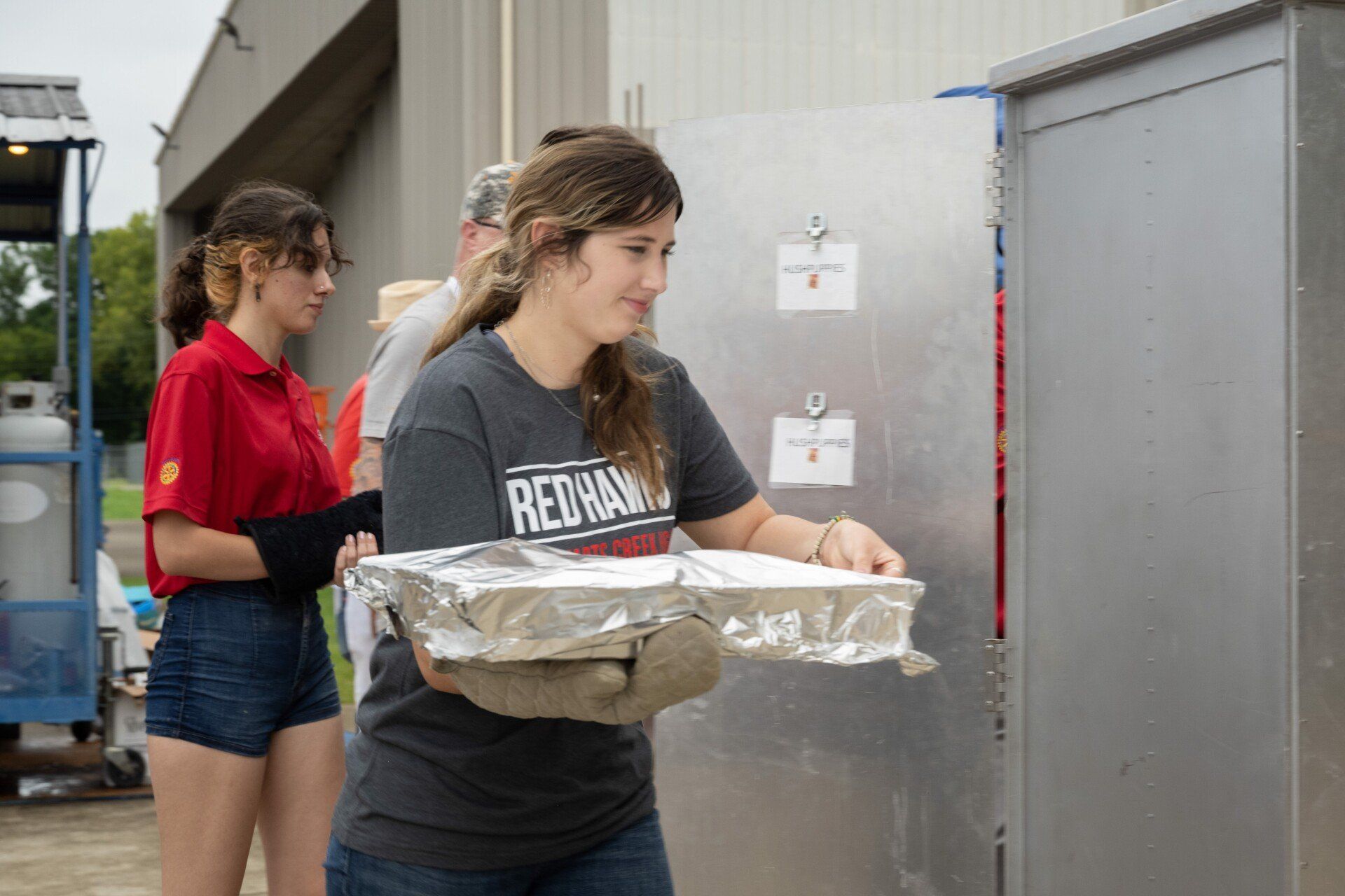 A woman is carrying a tray of food into a building.