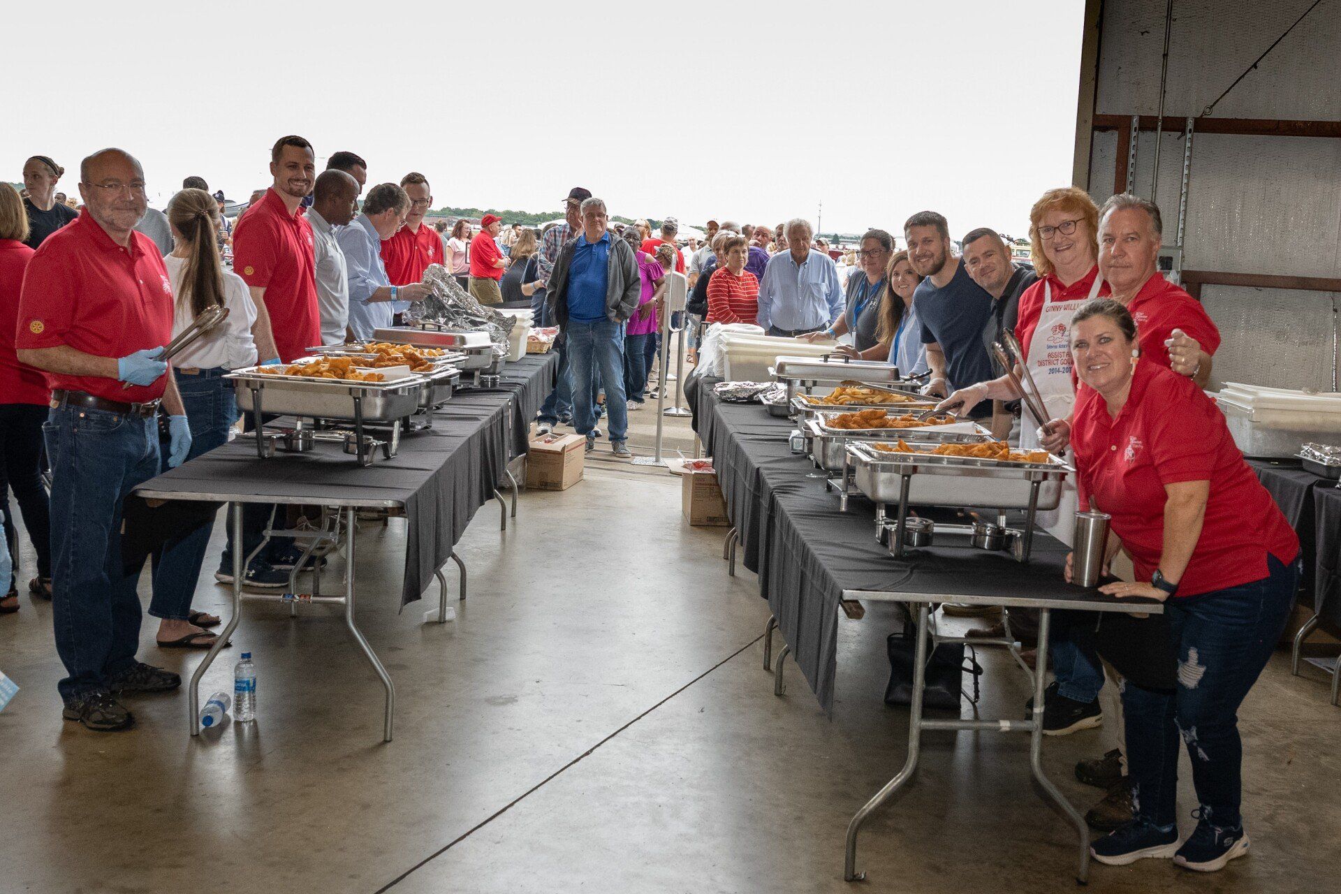 A group of people are standing around tables filled with food.