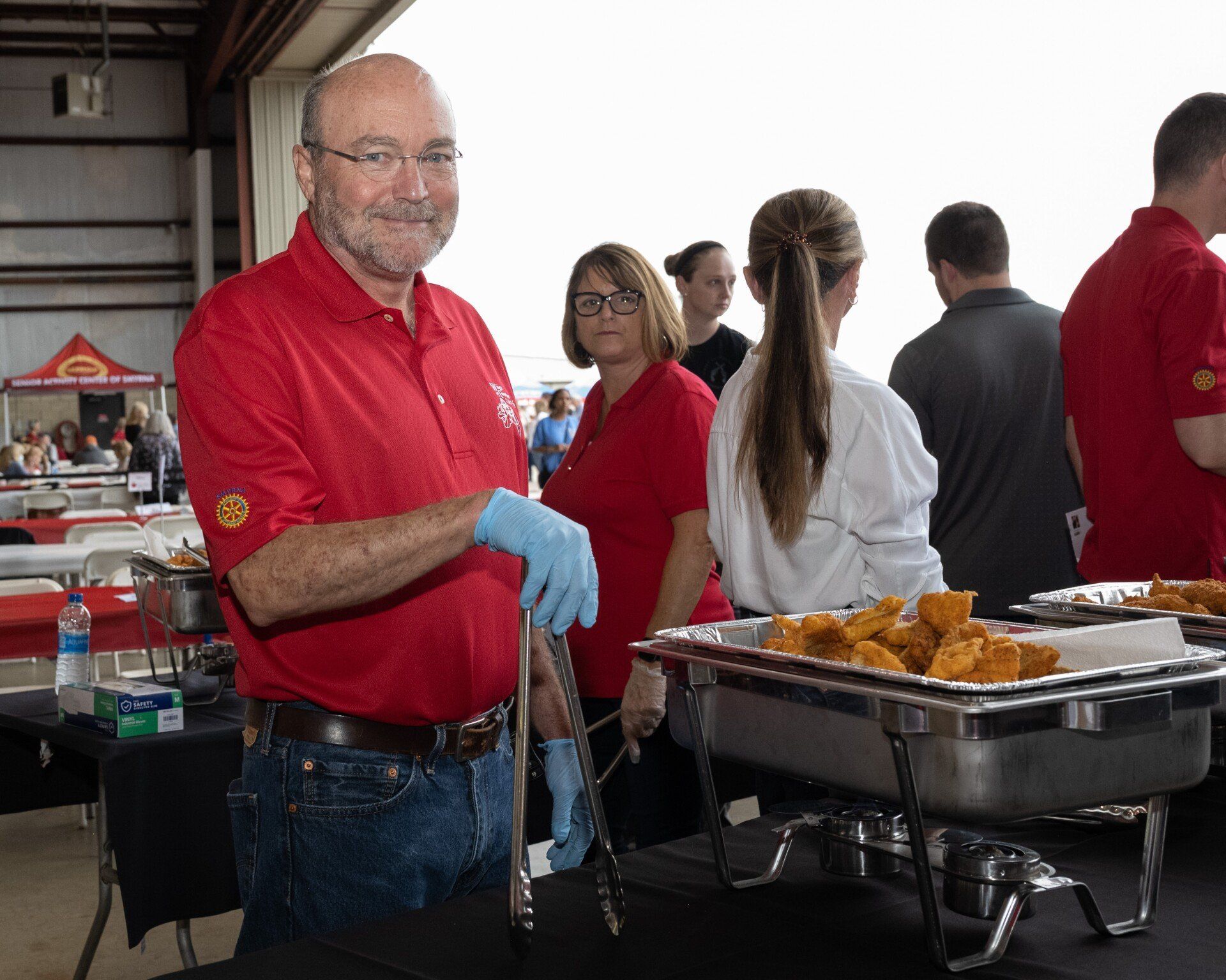 A man in a red shirt is standing in front of a buffet line.