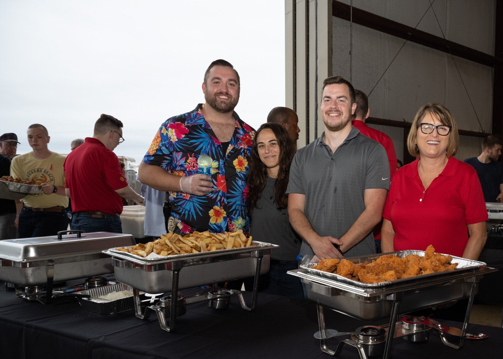 A group of people are standing in front of a table with trays of food.