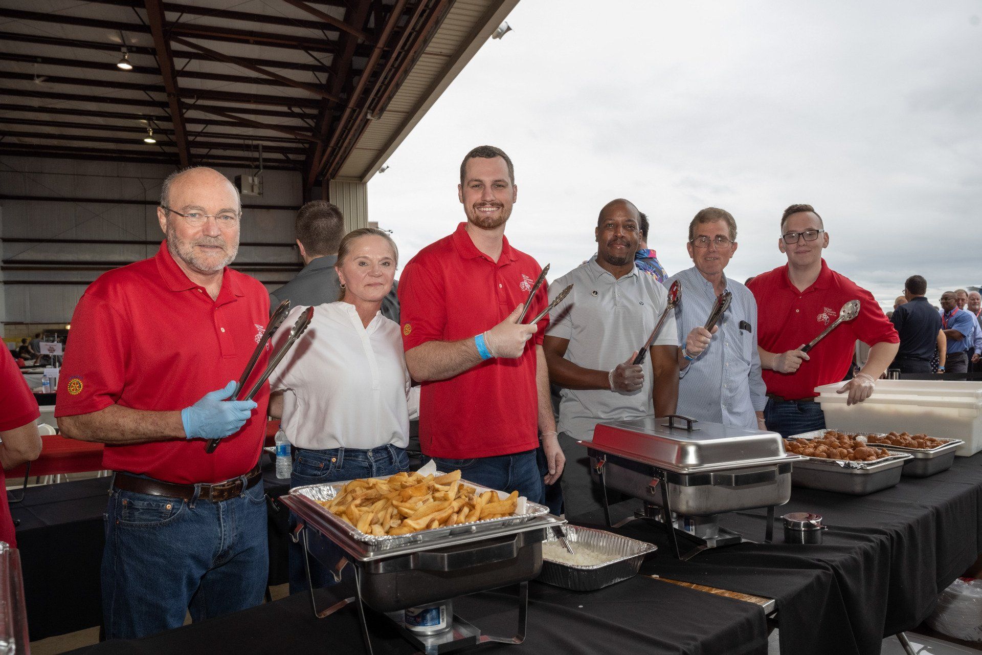 A group of people are standing around a table with trays of food.
