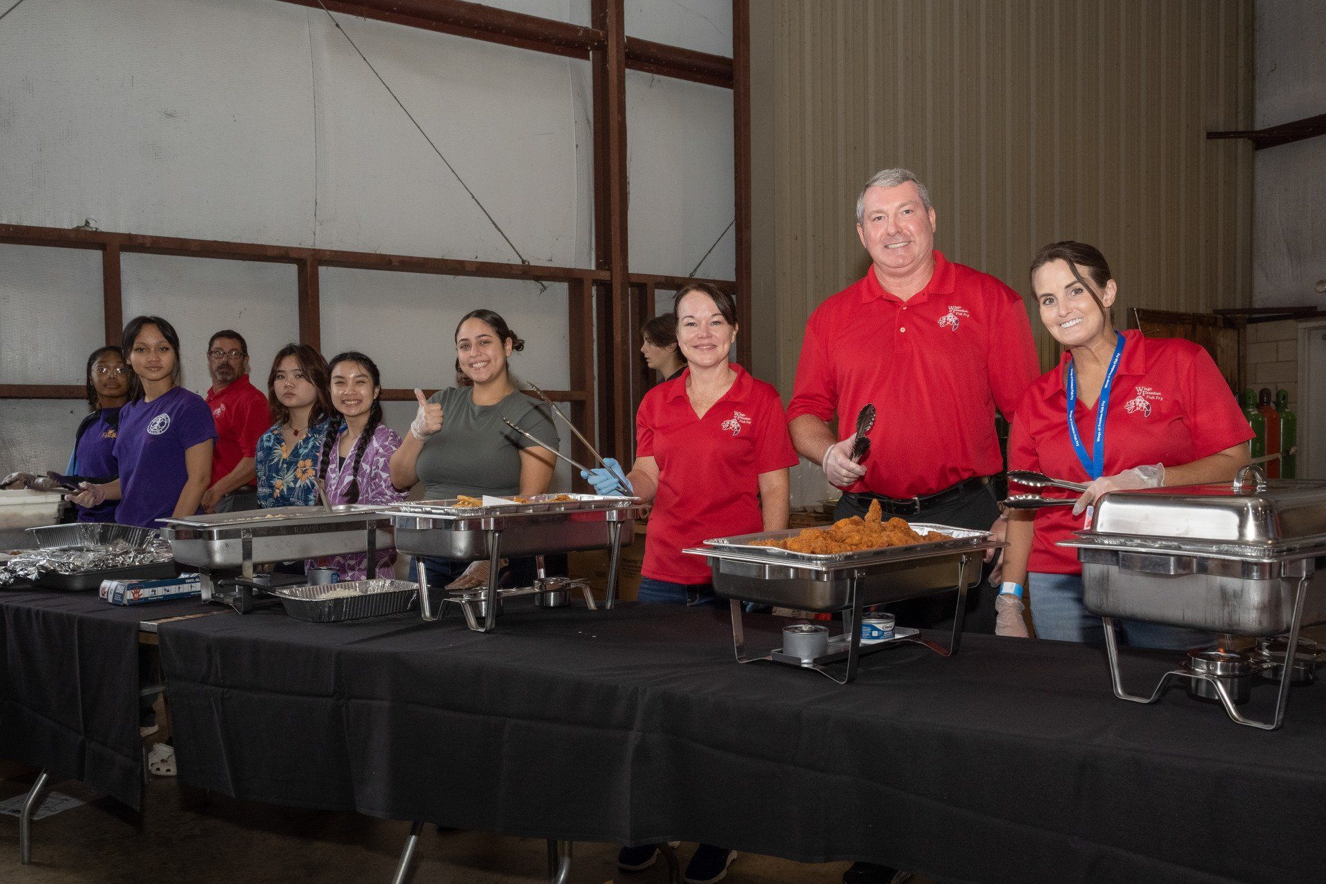 A group of people are standing in front of a buffet line.