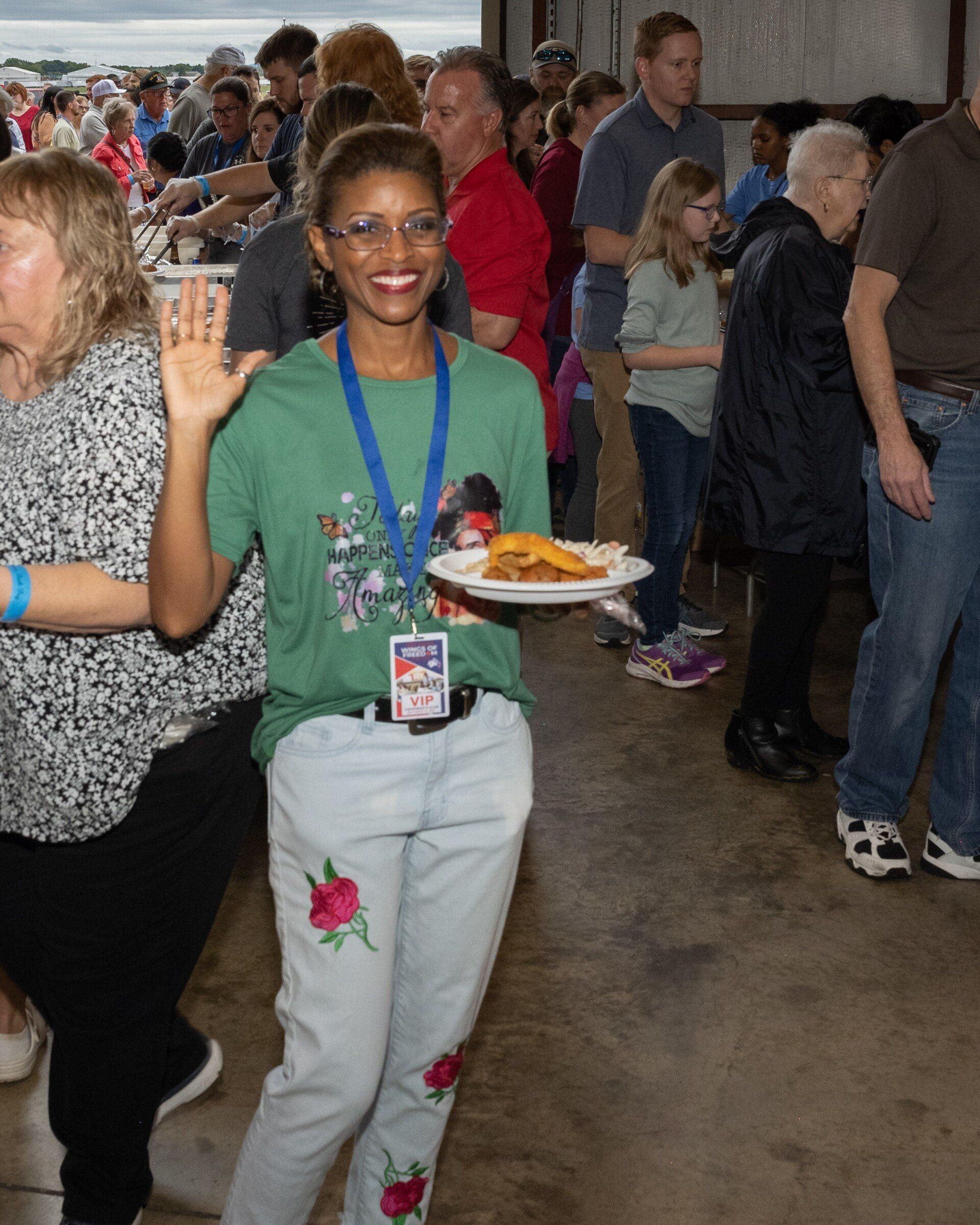 A woman in a green shirt is carrying a plate of food