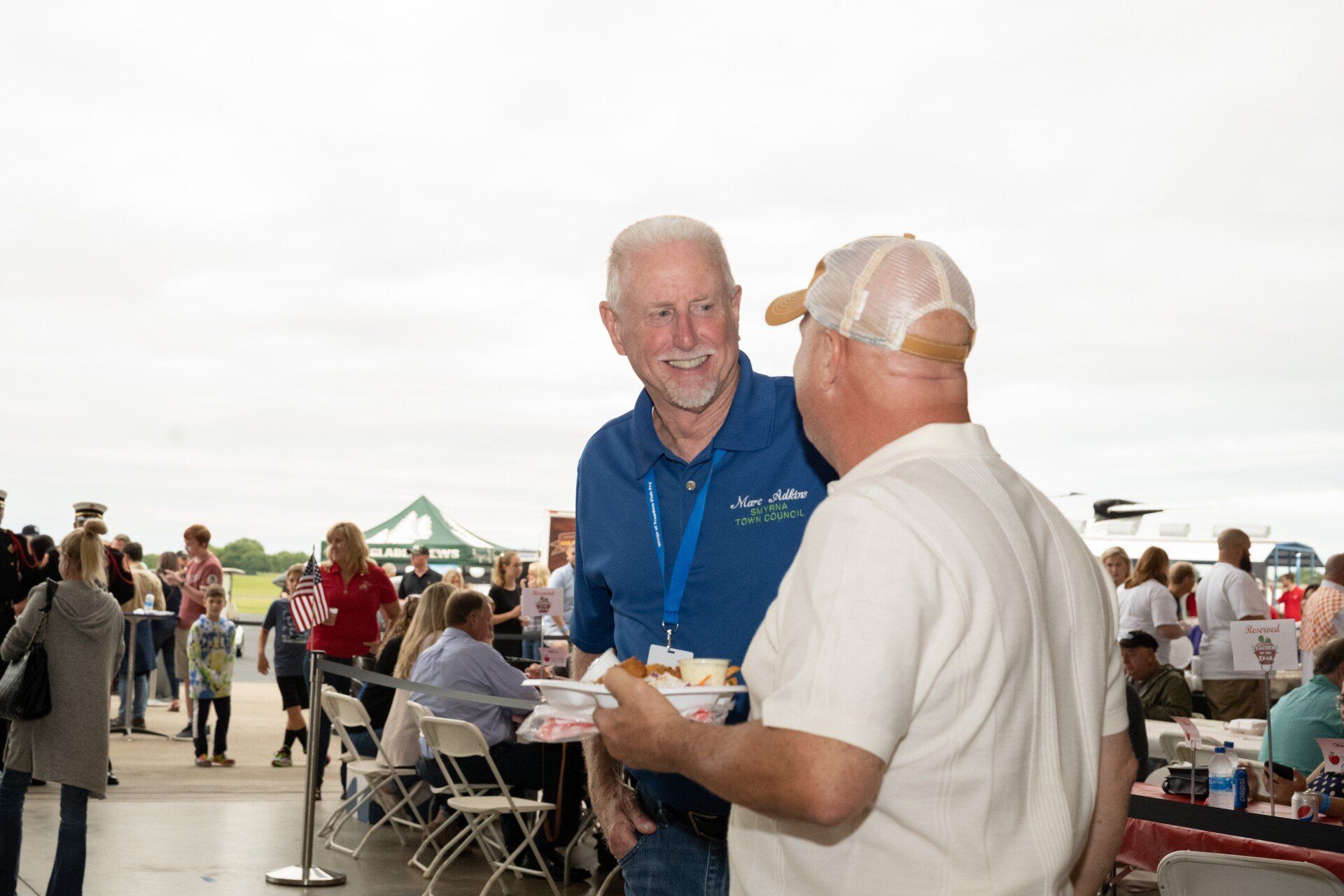 Two men are standing next to each other and talking at a convention.