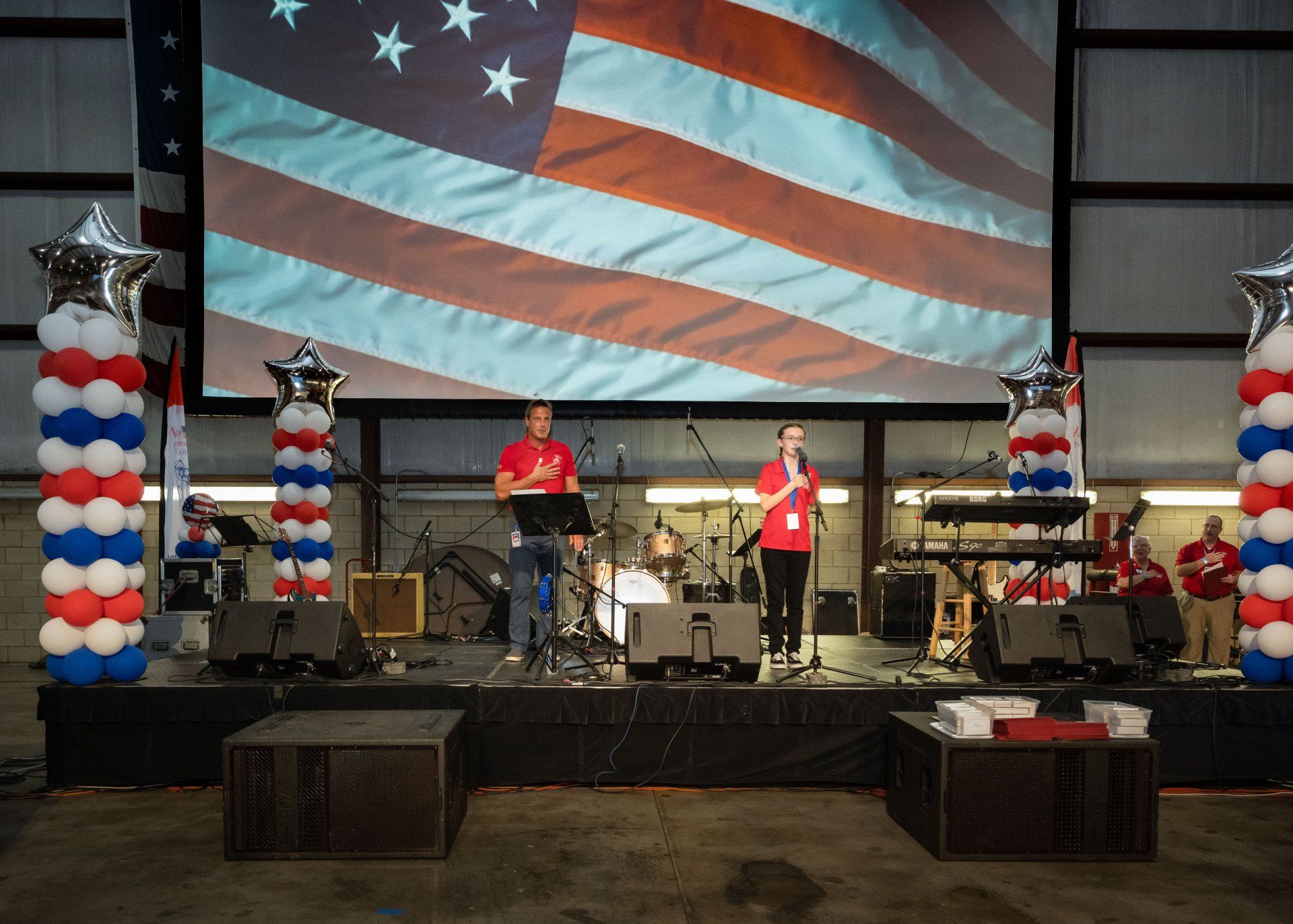 A band is playing on a stage in front of an american flag.