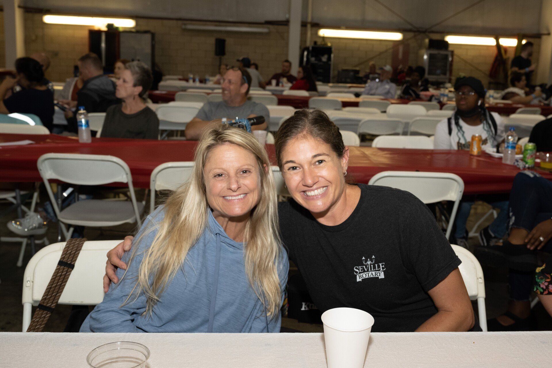 Two women are posing for a picture while sitting at a table