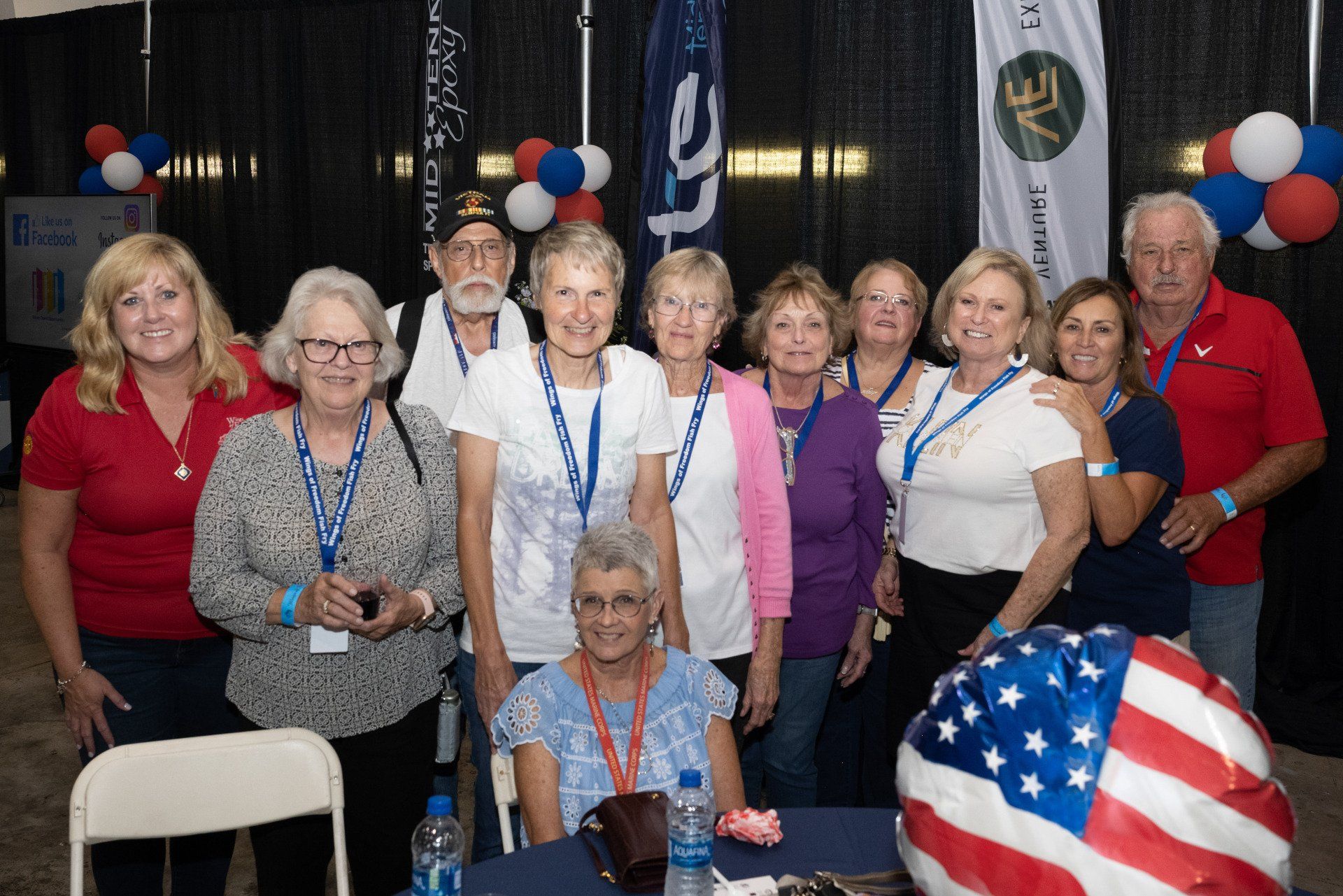 A group of people are posing for a picture in front of an american flag.