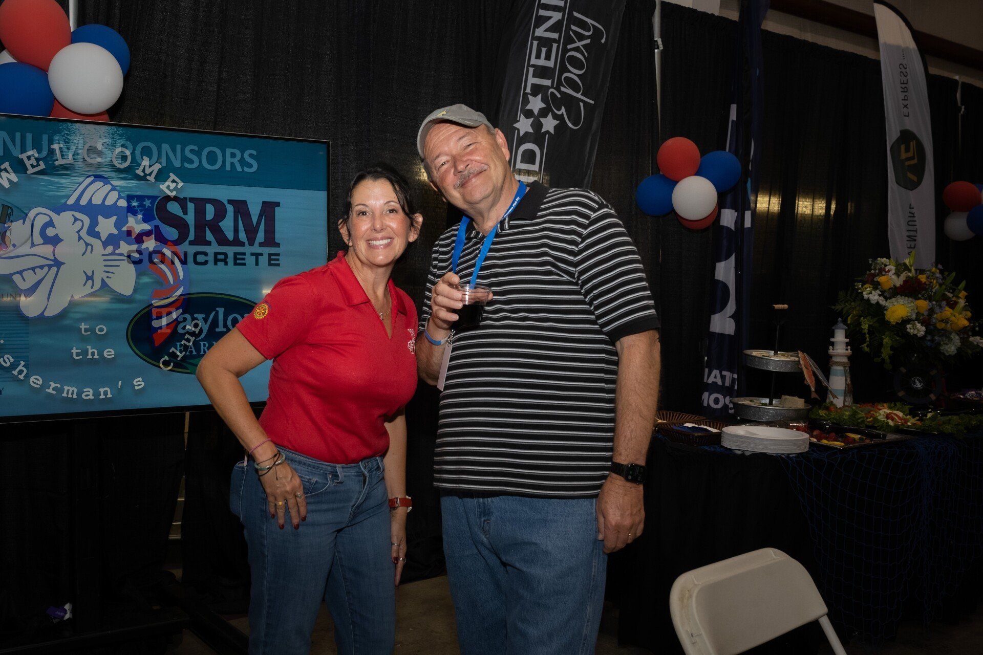 A man and a woman are posing for a picture in front of a sign that says sponsors.