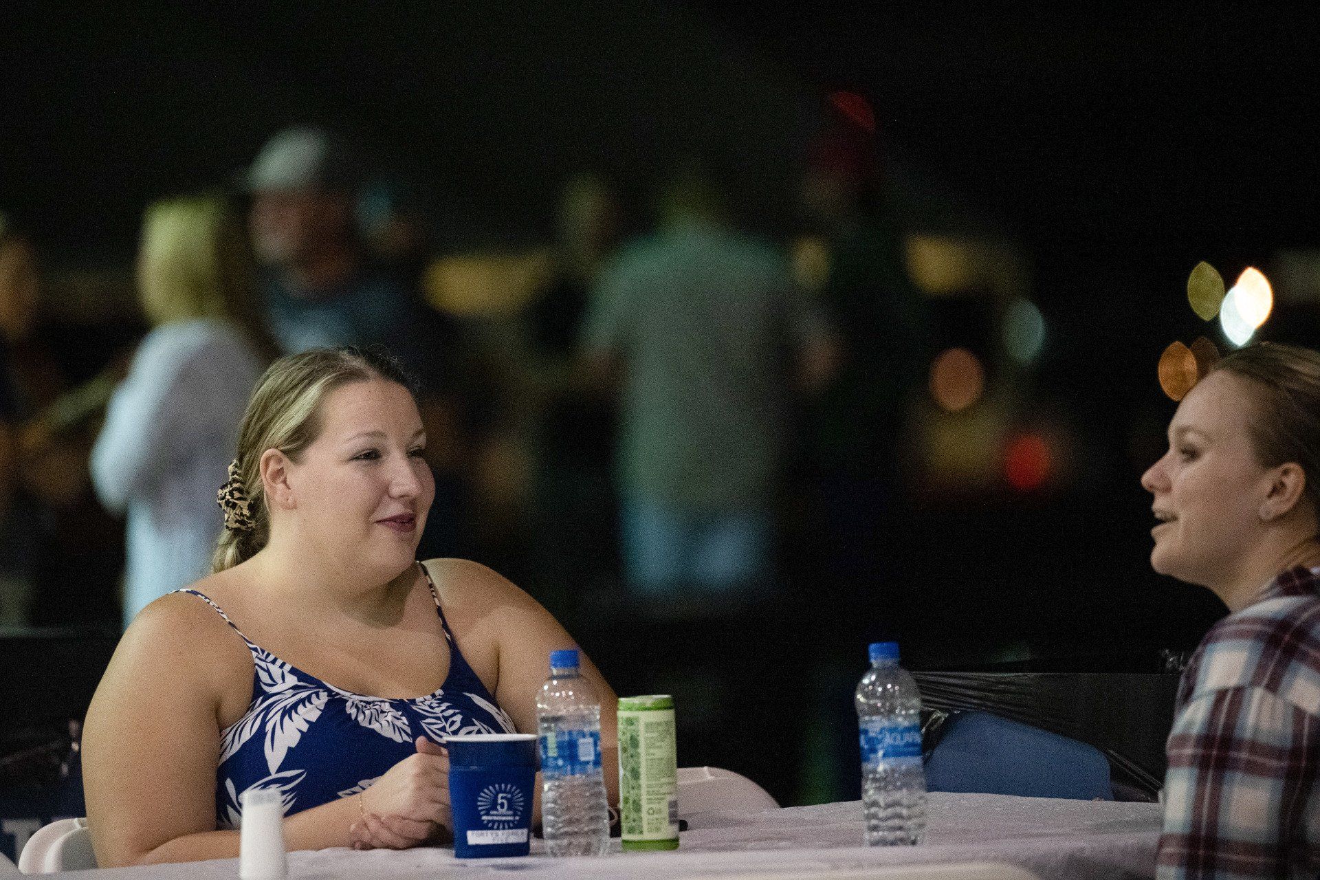 Two women are sitting at a table talking to each other.