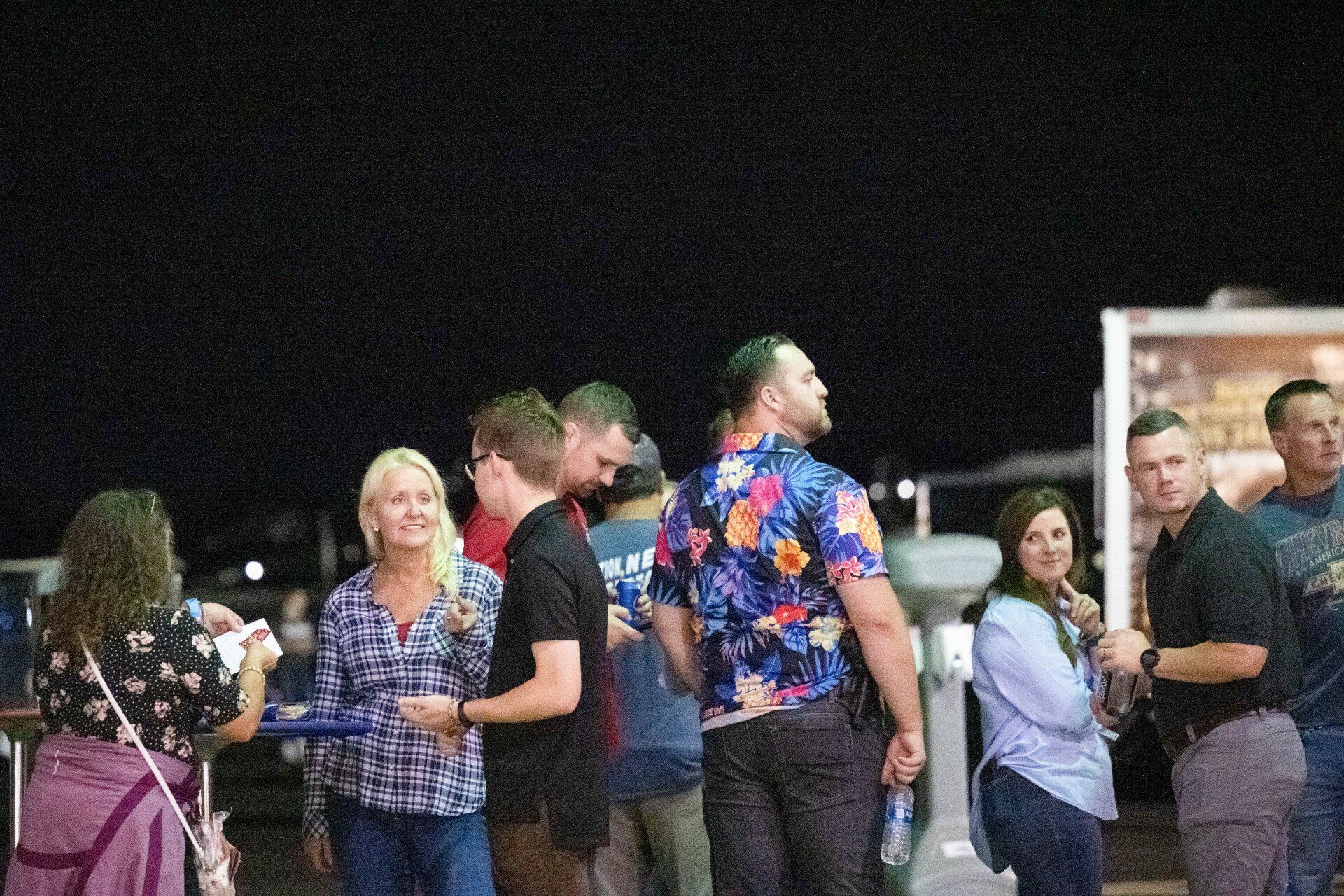 A group of people are standing in a line at night.