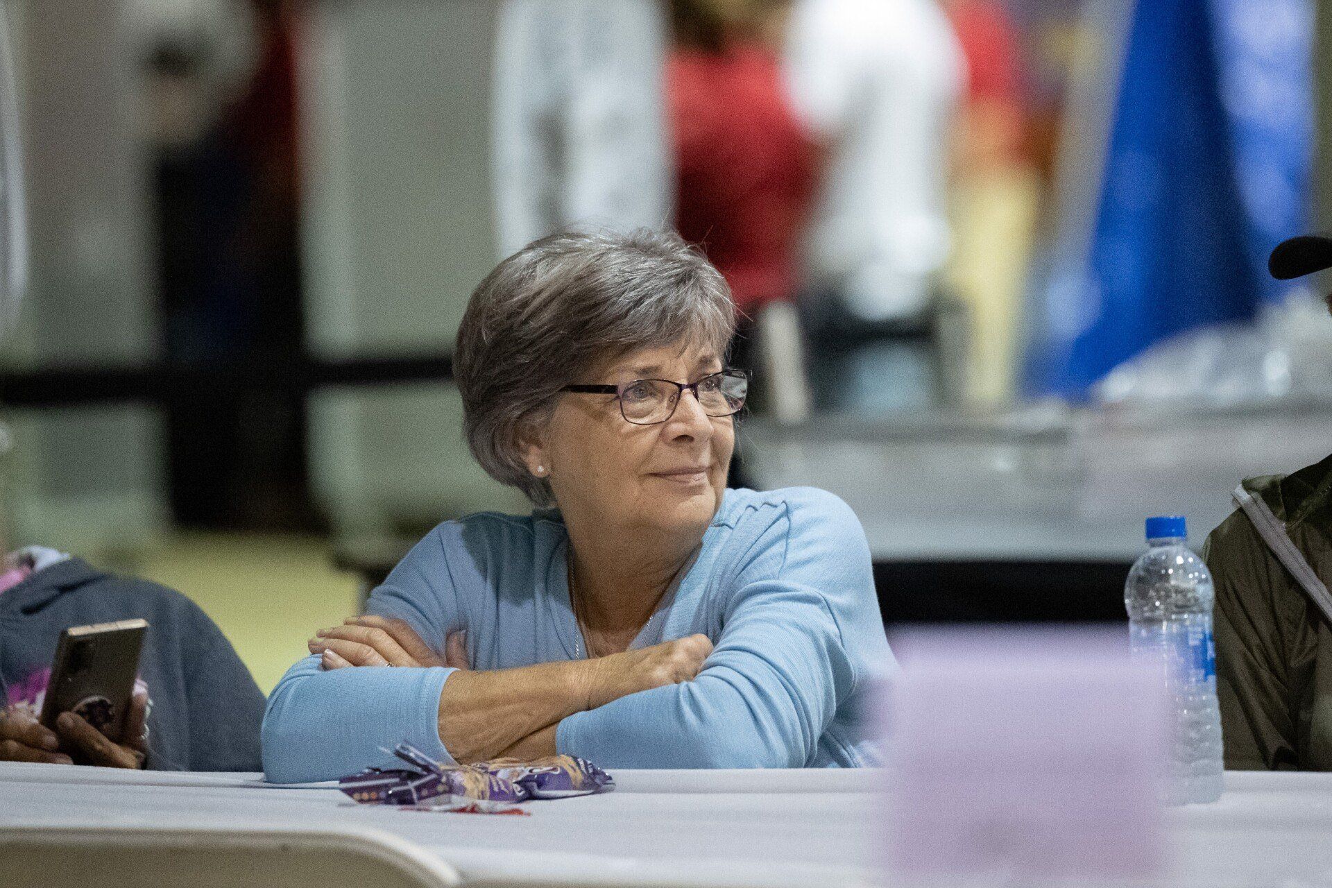 A woman is sitting at a table with her arms crossed.