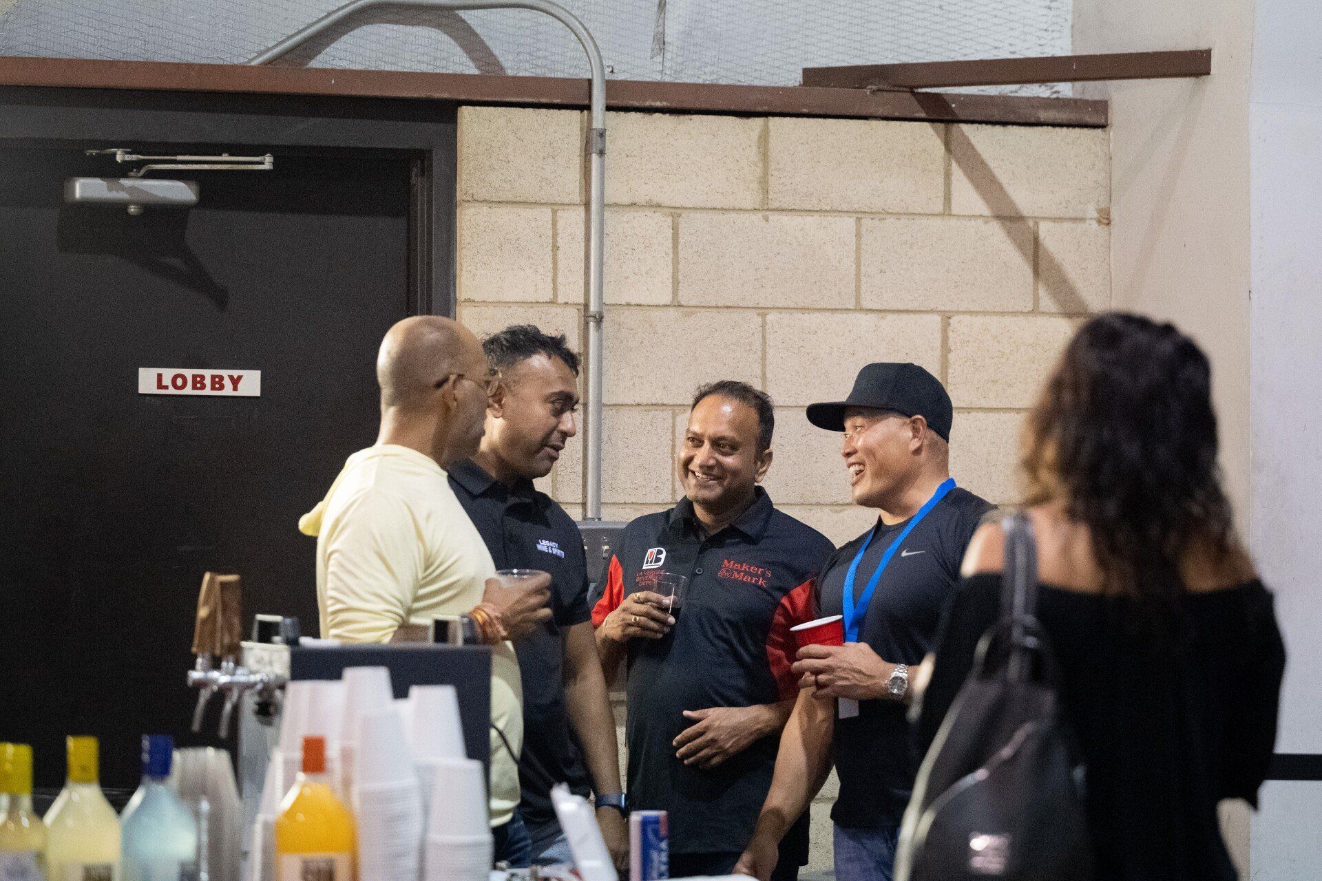 A group of men are standing around a table talking to each other.