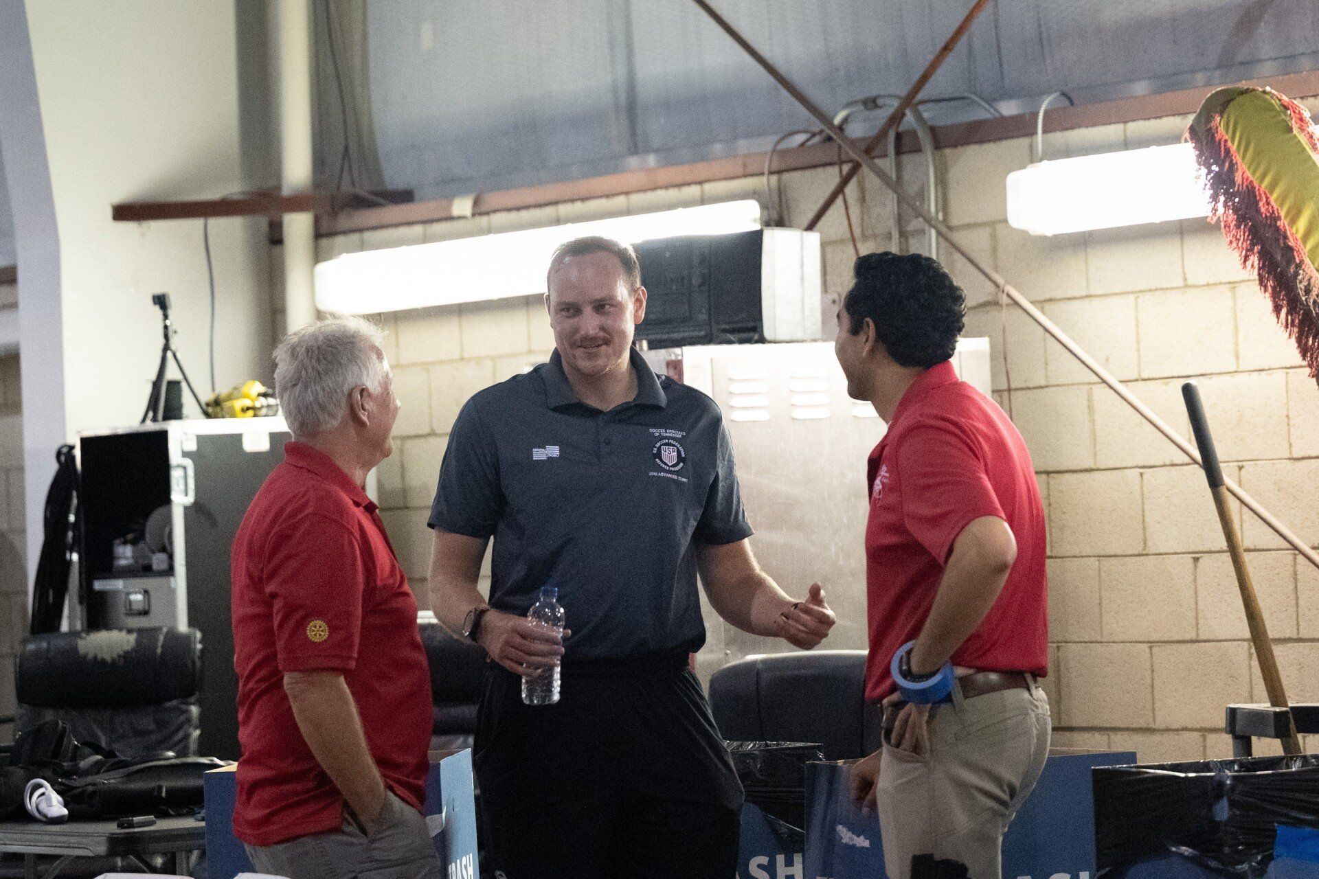 Three men are standing in a room and talking to each other