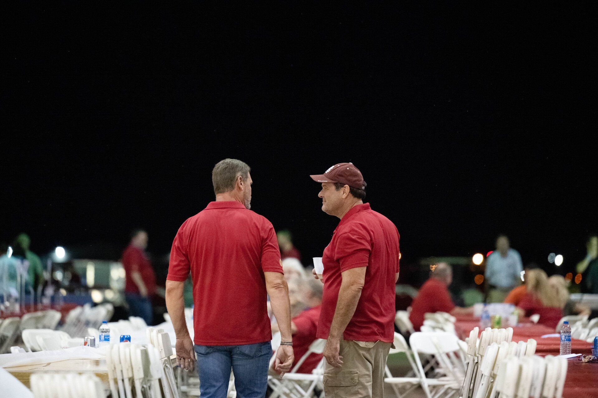 Two men in red shirts are standing next to each other in front of a crowd of people.