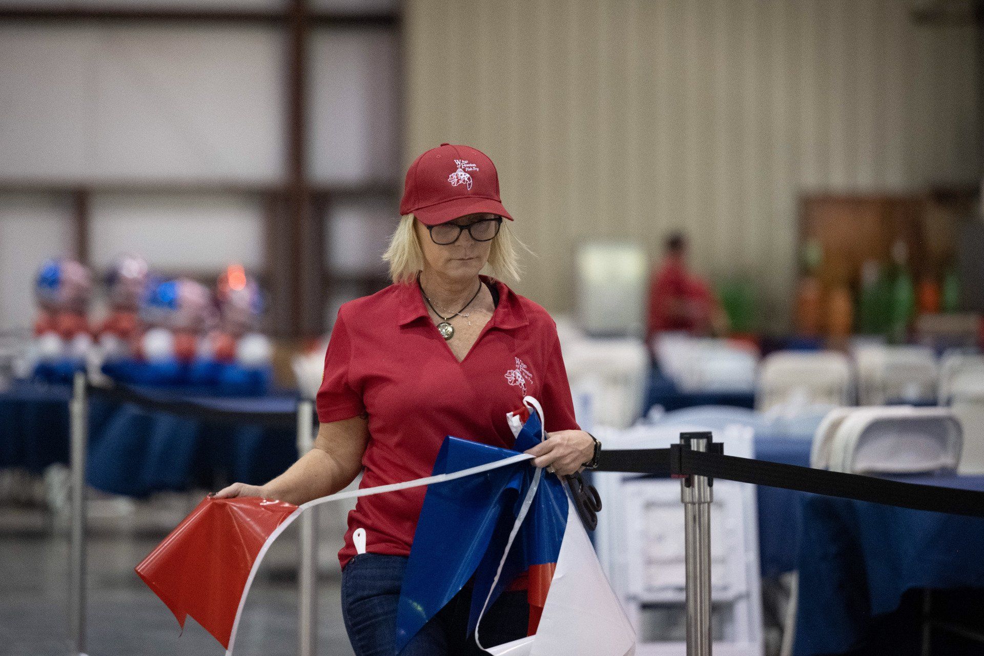 A woman in a red shirt is holding a red , white and blue flag.