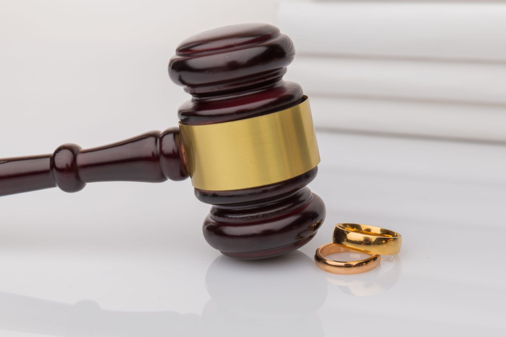 Judge’s gavel beside gold wedding rings on a glossy surface