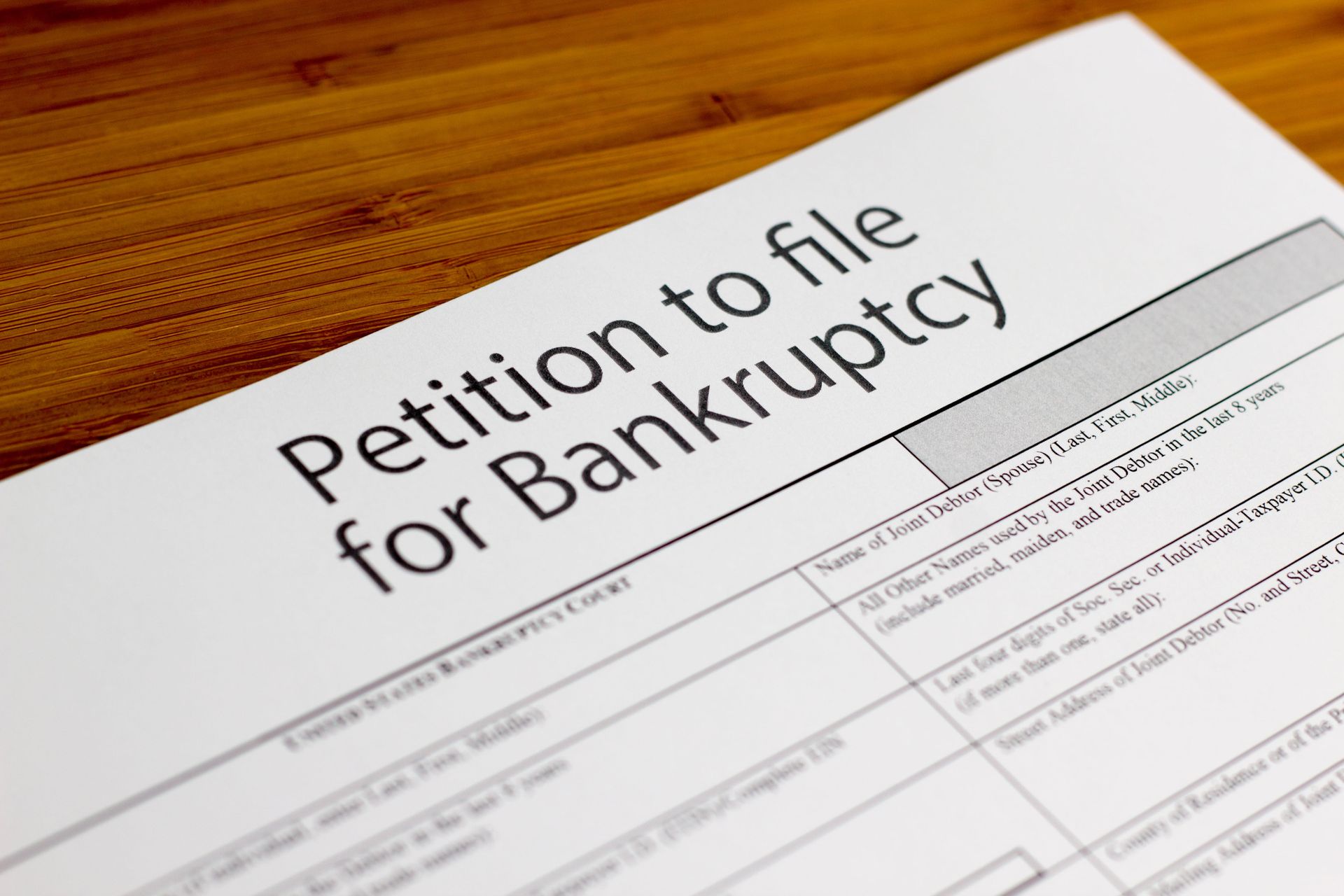 Petition to file for bankruptcy form on a wooden desk, viewed at an angle