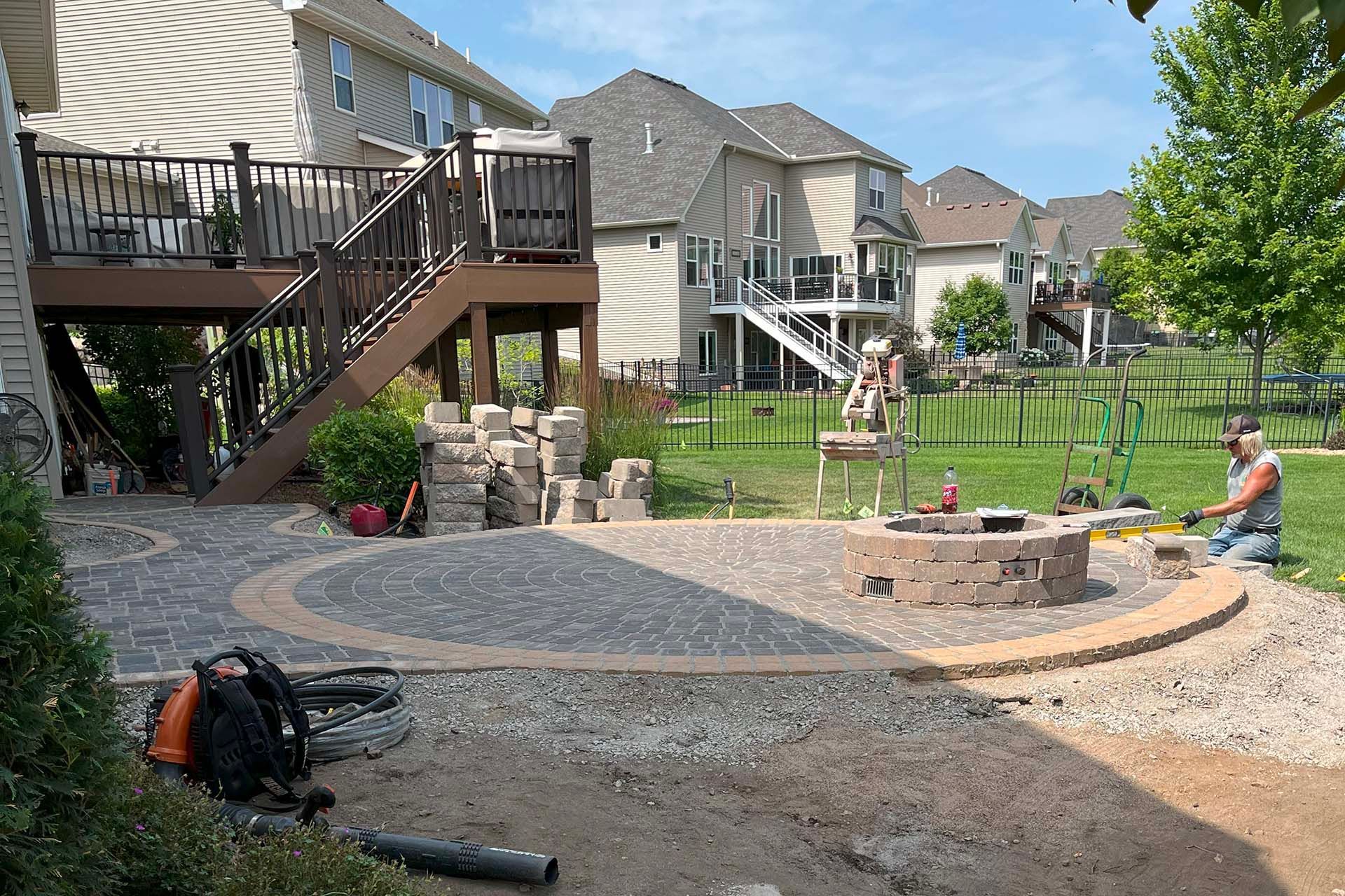 A firepit being built into a circular patio in a backyard.