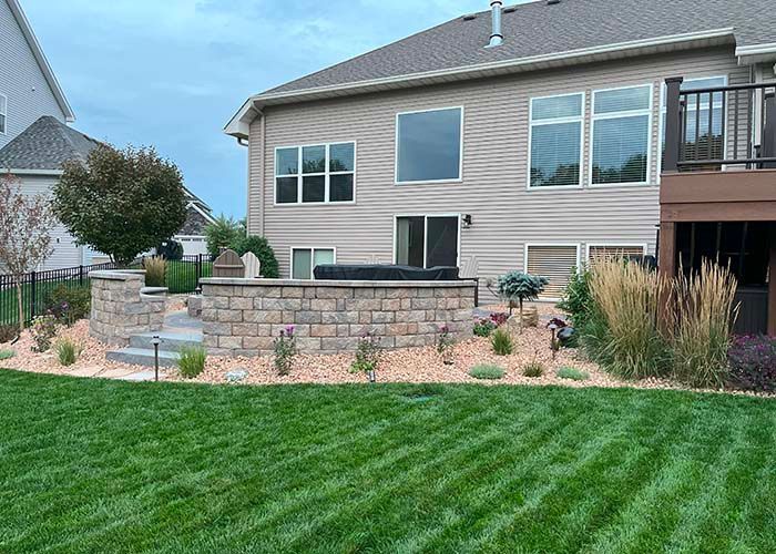 A large house with a large patio with a retaining wall.