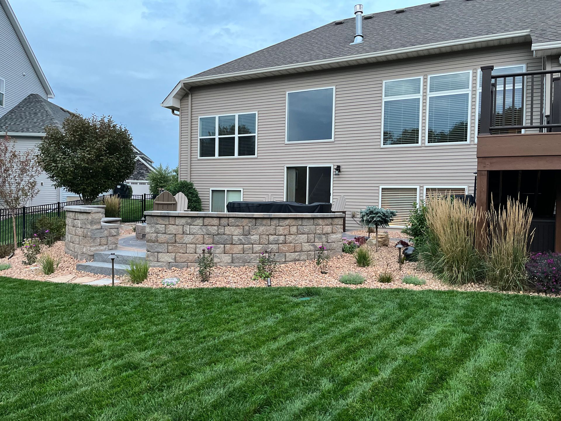 A large house with a large patio and retaining wall.