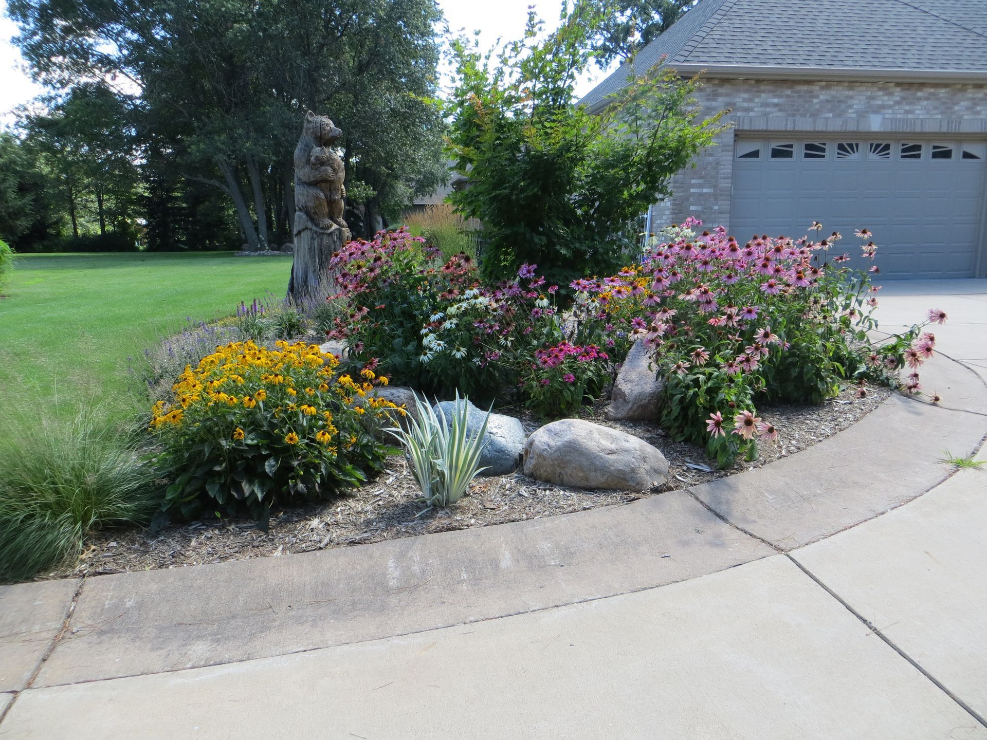 A garden with flowers and rocks next to a driveway.