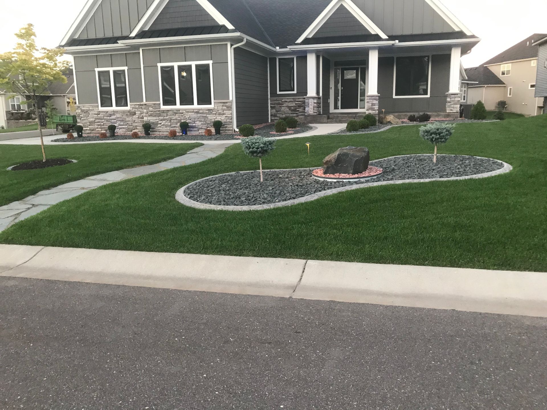 A house with a lush green lawn in front of it and a rock garden.
