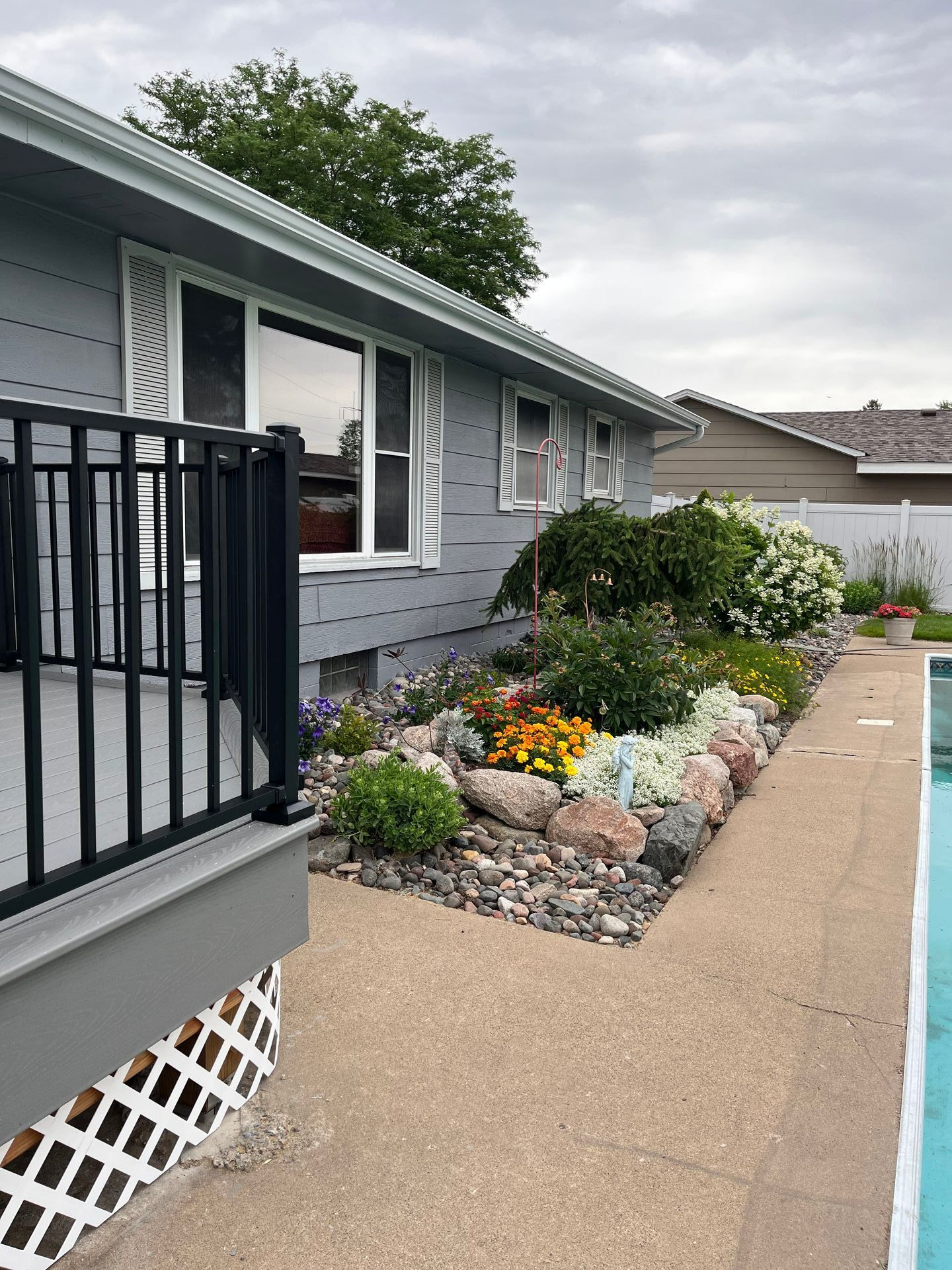 A house with a rock garden in front of it filled with plants and shrubs.