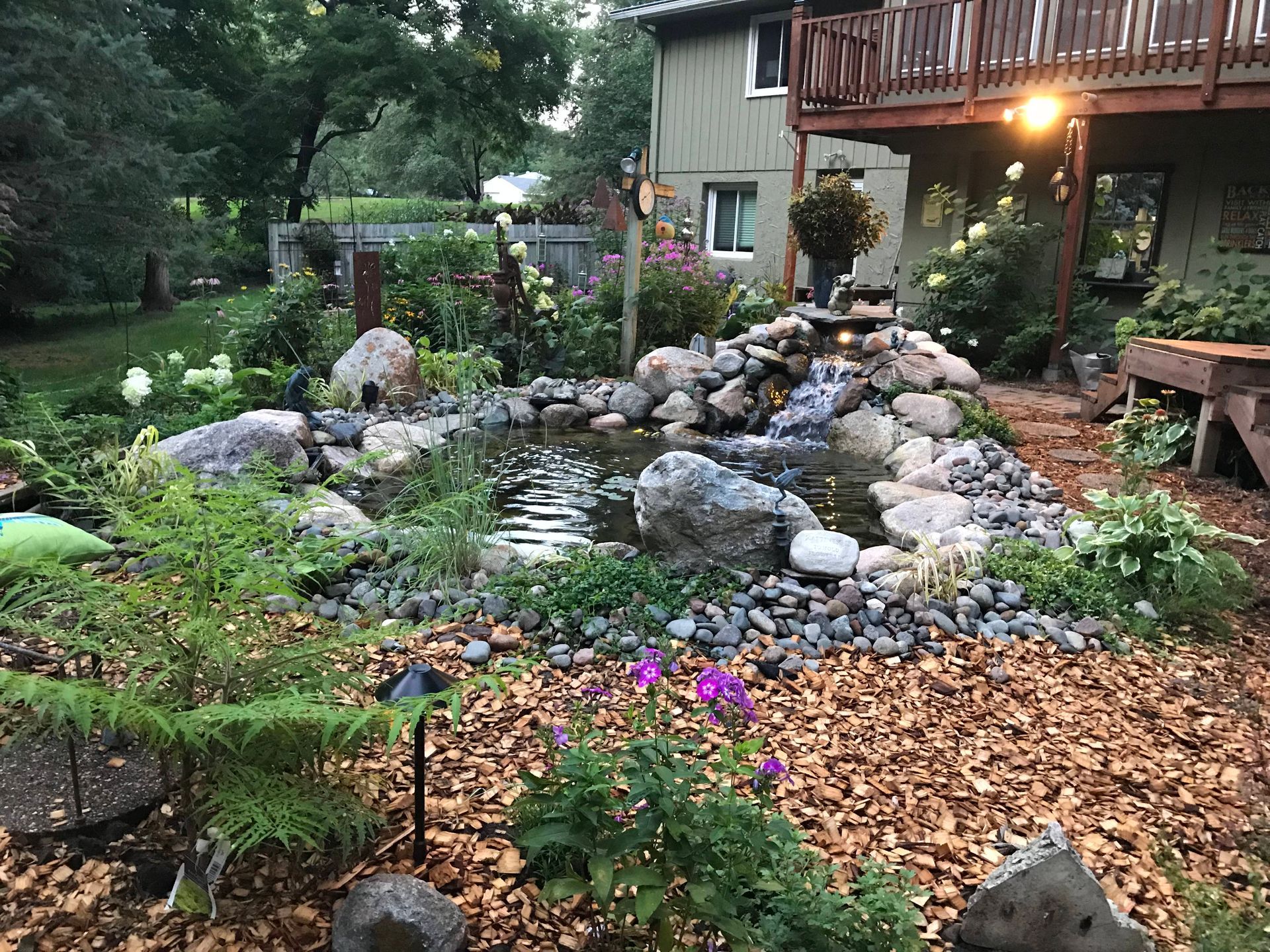 There is a pond in the middle of a garden in front of a house.