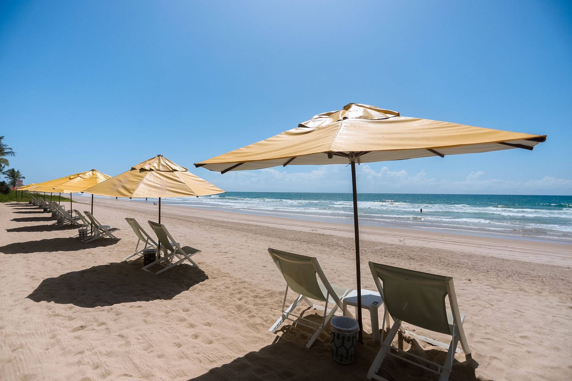 Espreguiçadeiras e guarda-sóis na praia de Porto de Galinhas; mar e areia branca.