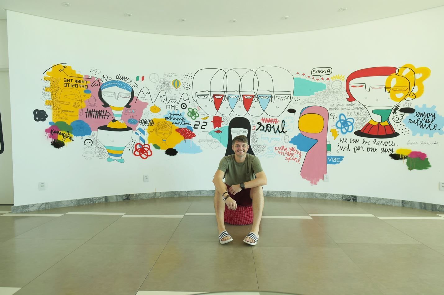 Lucas lamenha com o mural no lobby do hotel.
