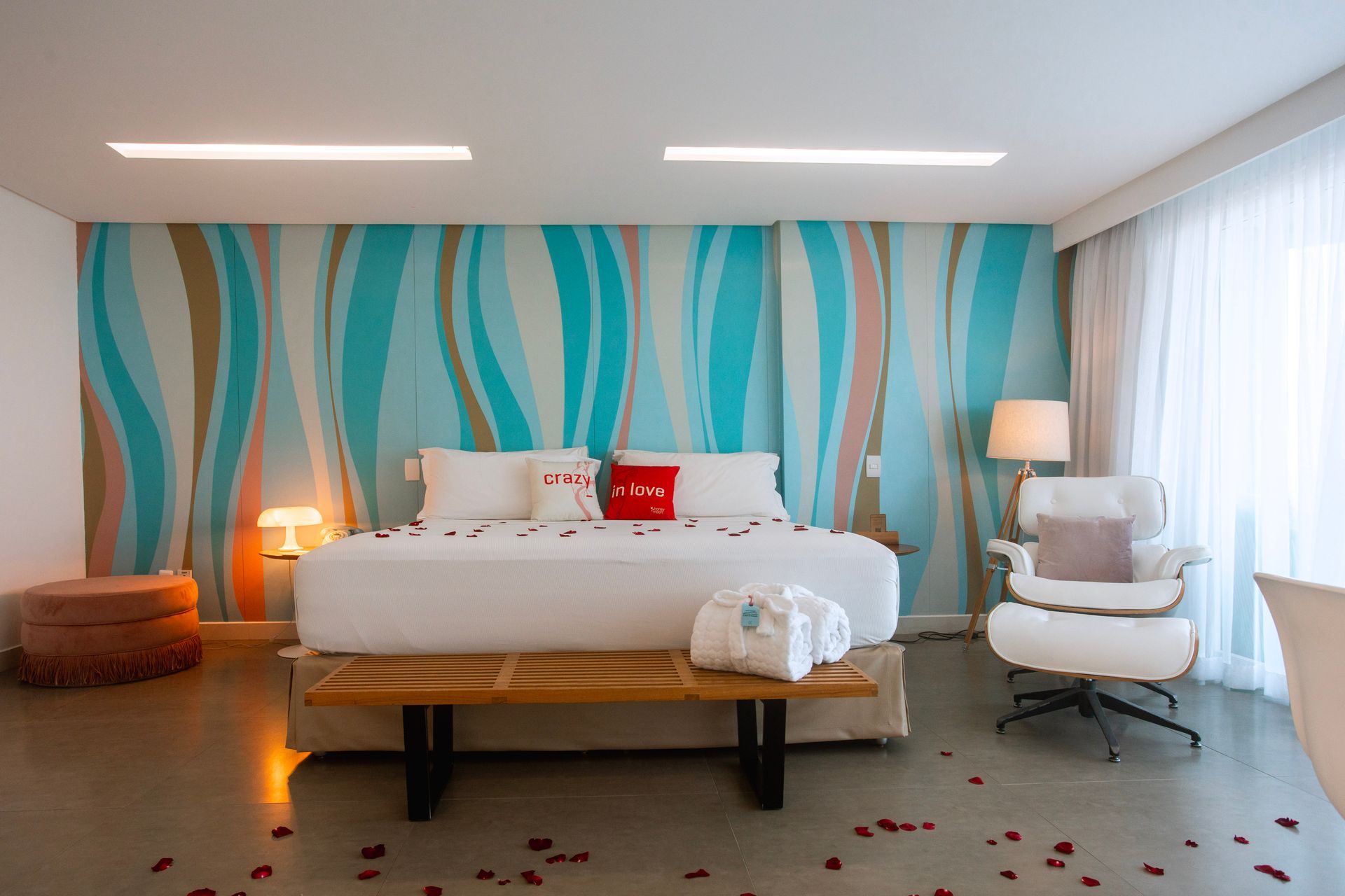 Suíte romântica com cama king, pétalas de rosas, decoração moderna e ambiente acolhedor para casais.